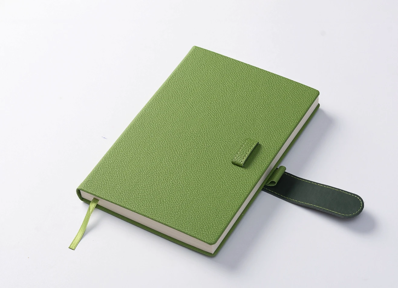 High-angle view of a closed lime green diary resting on a white surface, highlighting the textured cover and secure dark green loop closure.