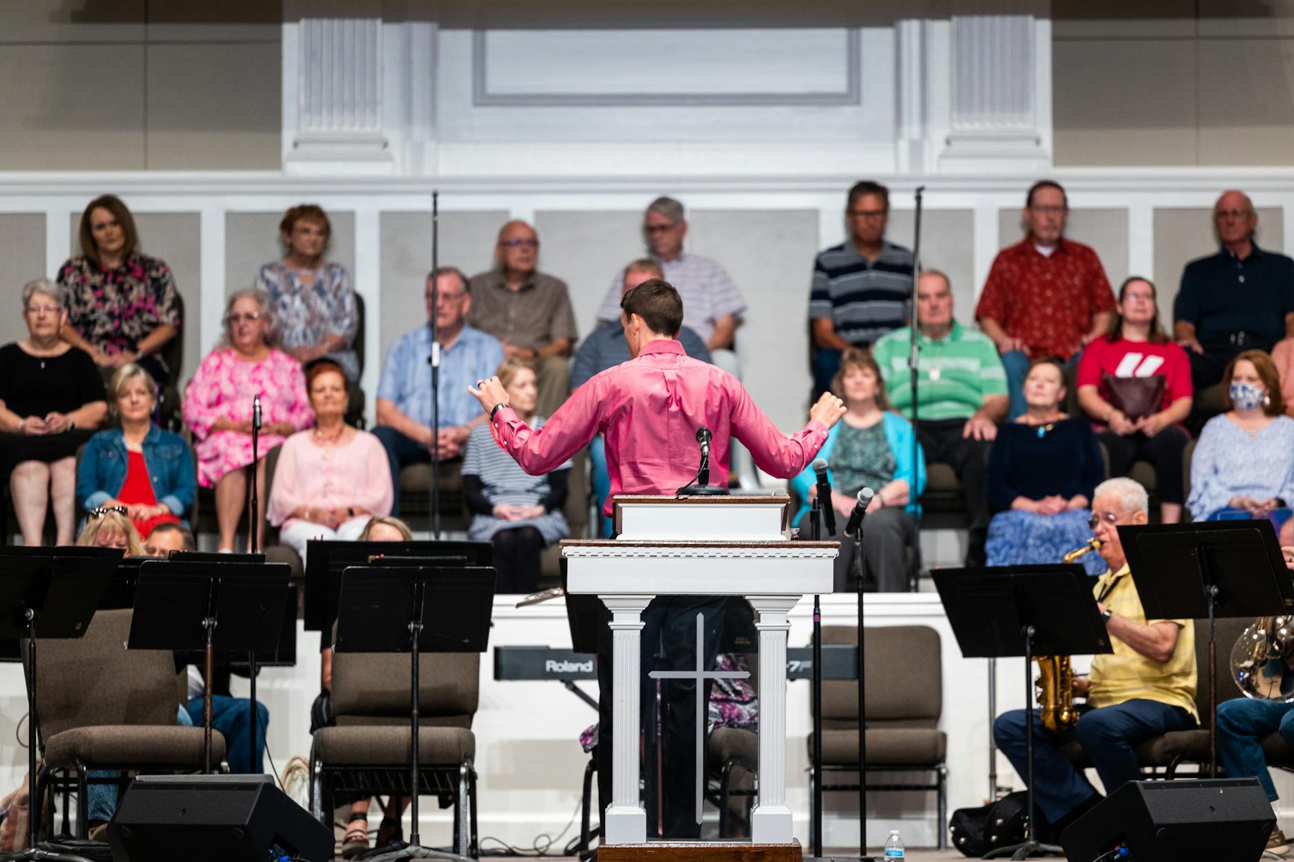 A vocal coach sitting at a grand piano guiding a solo student through breath control exercises in a private studio.