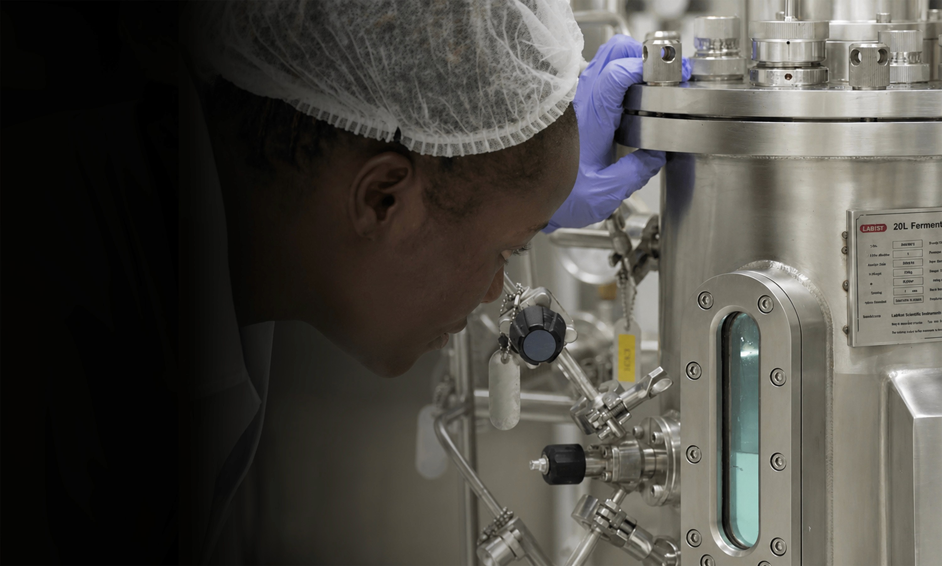 Lab technician inspecting a stainless steel bioreactor at Essential's Nairobi facility