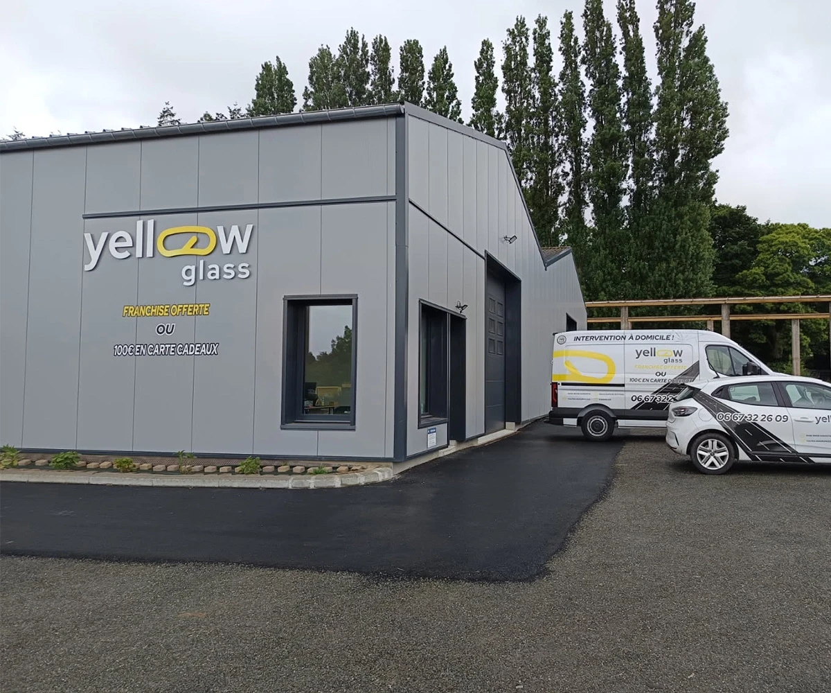 Façade d'un bâtiment jaune glass, avec un fourgon et une voiture garés devant. Affichage du nom de l'entreprise.