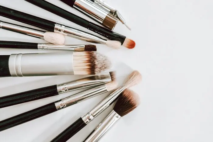 A collection of black and brown makeup brushes laid out in a fan