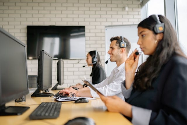 Three customer support agetns sitting at a desk