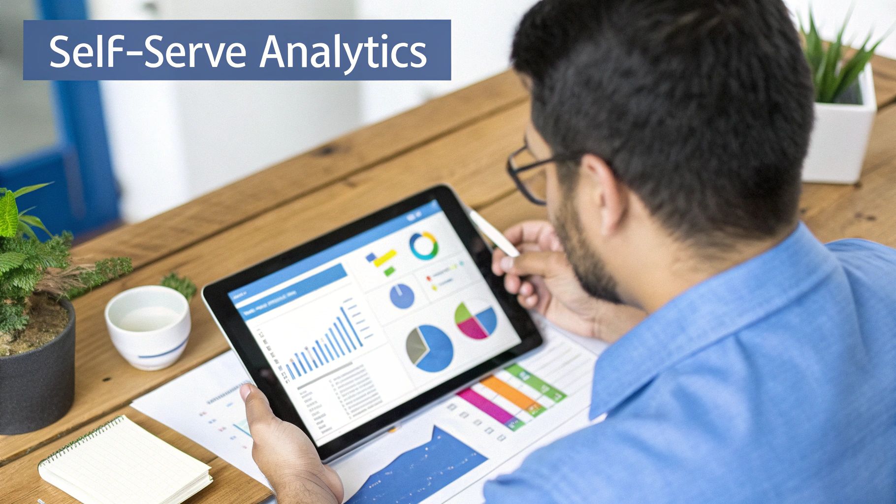 Man using a tablet displaying data analytics and charts, highlighting self-serve analytics.