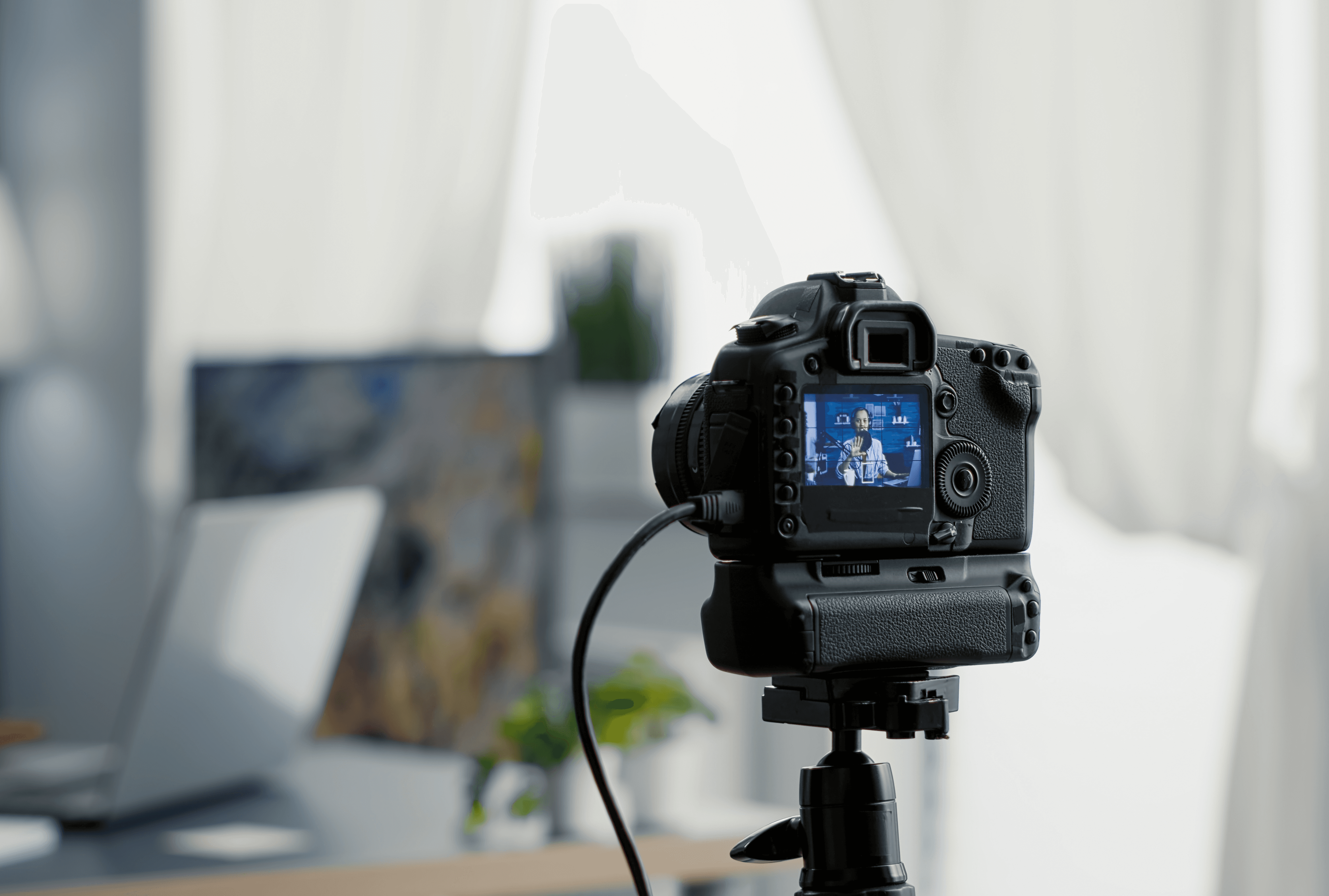 Camera recording content with blurry laptop in background