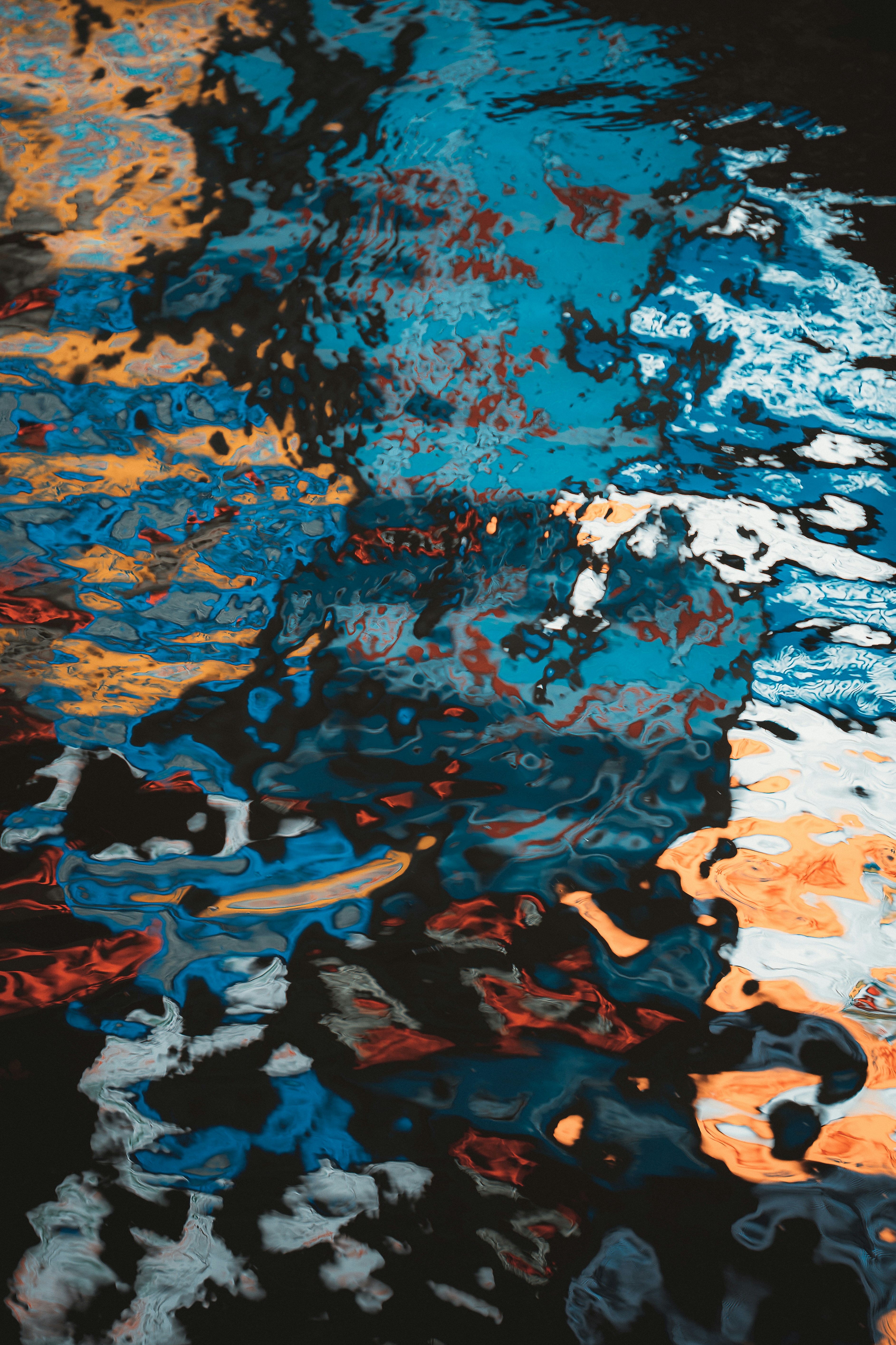 Close-up portrait of a person wearing a gray insulated hooded jacket with the hood up, showing their face framed by the hood against a light background.