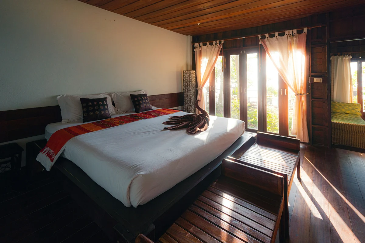 Family suite with a large bed, warm wooden floors, and sunlight coming through garden-facing doors.