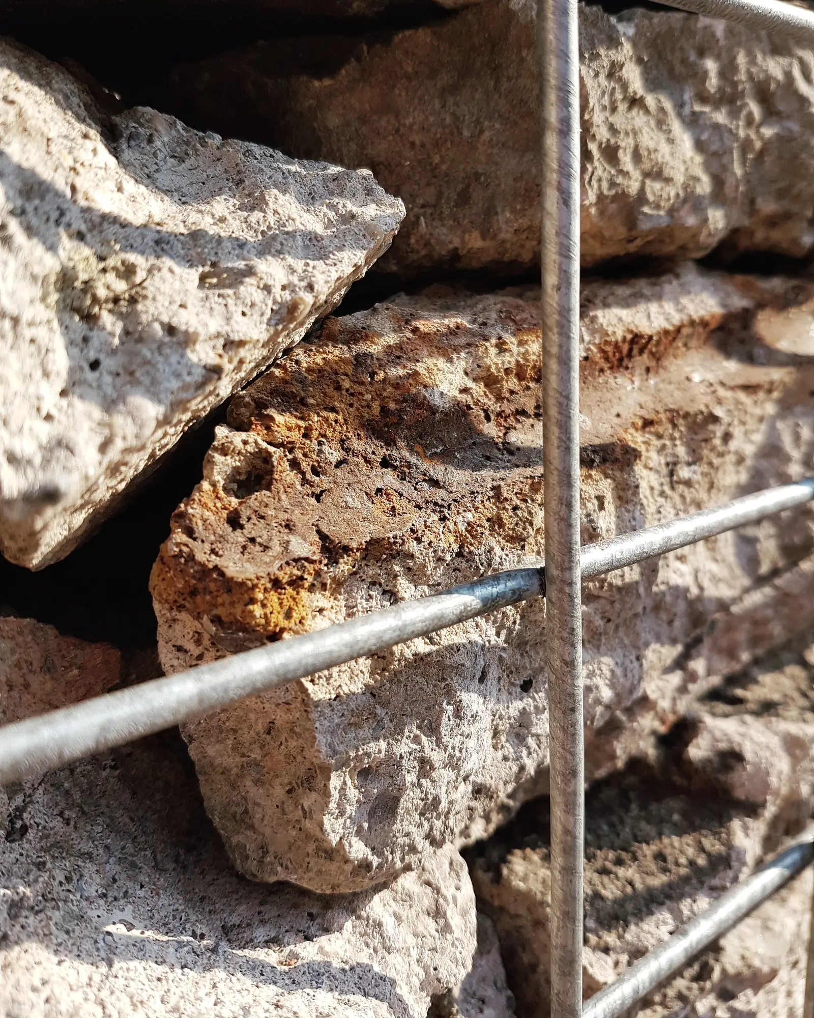 Close-up of stacked rocks with a metal framework, showing textures and earthy tones.