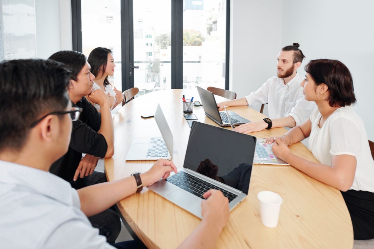 People sitting at a table with laptops and papers.