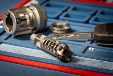 Disassembled vehicle ignition and lock components on a workbench during locksmith repair.