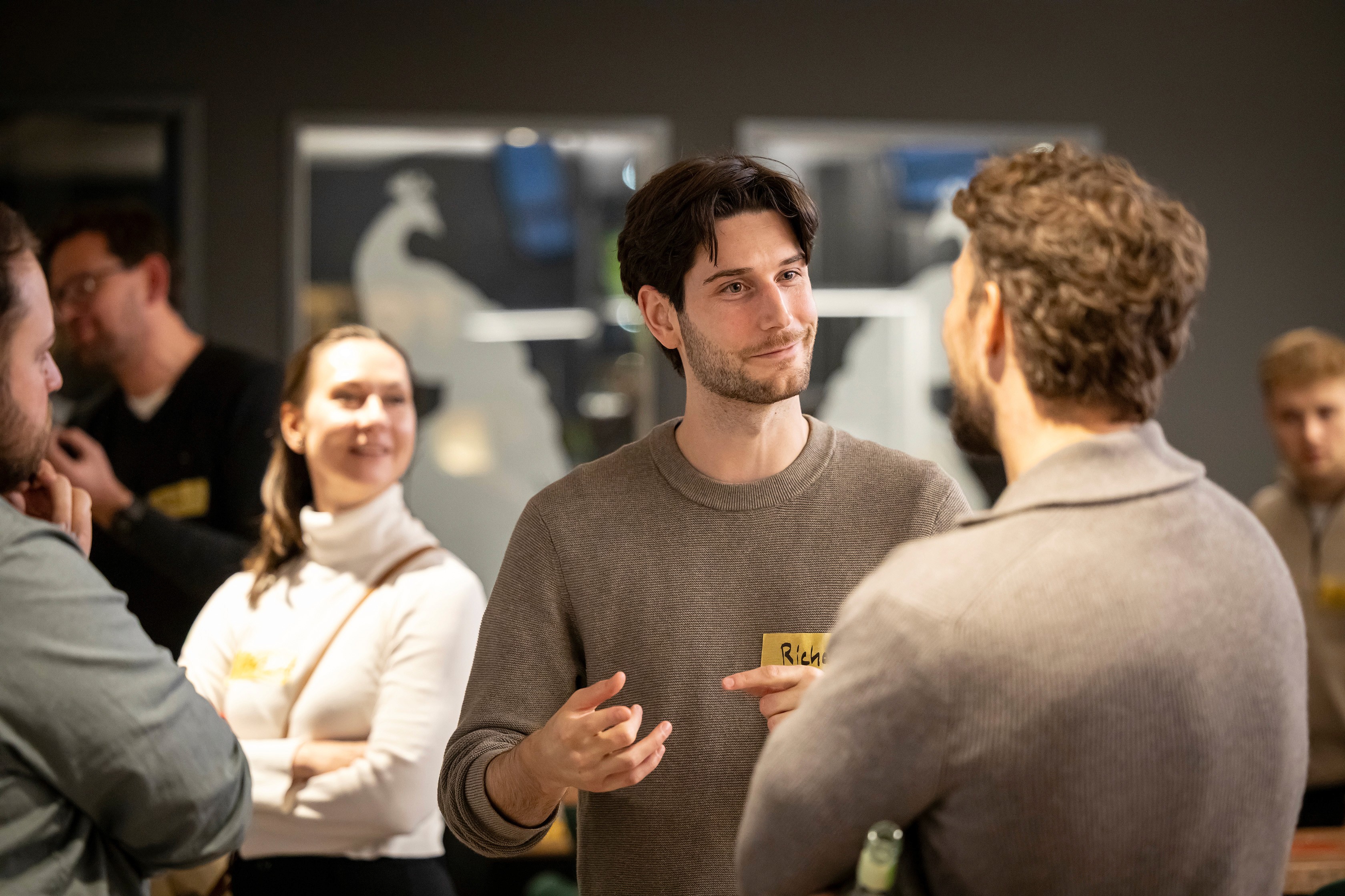 People crossing a busy street with cars and buildings.