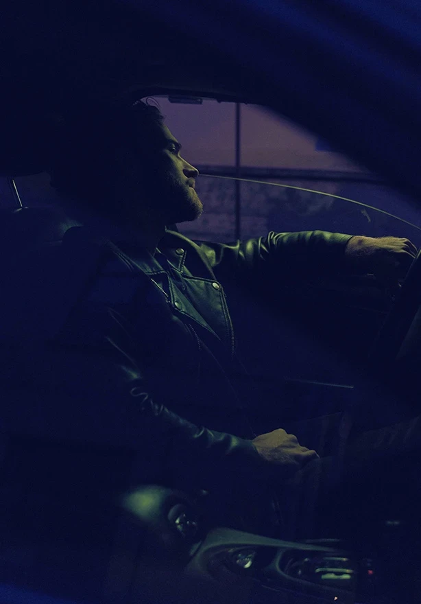 Man driving at night with hand on steering wheel