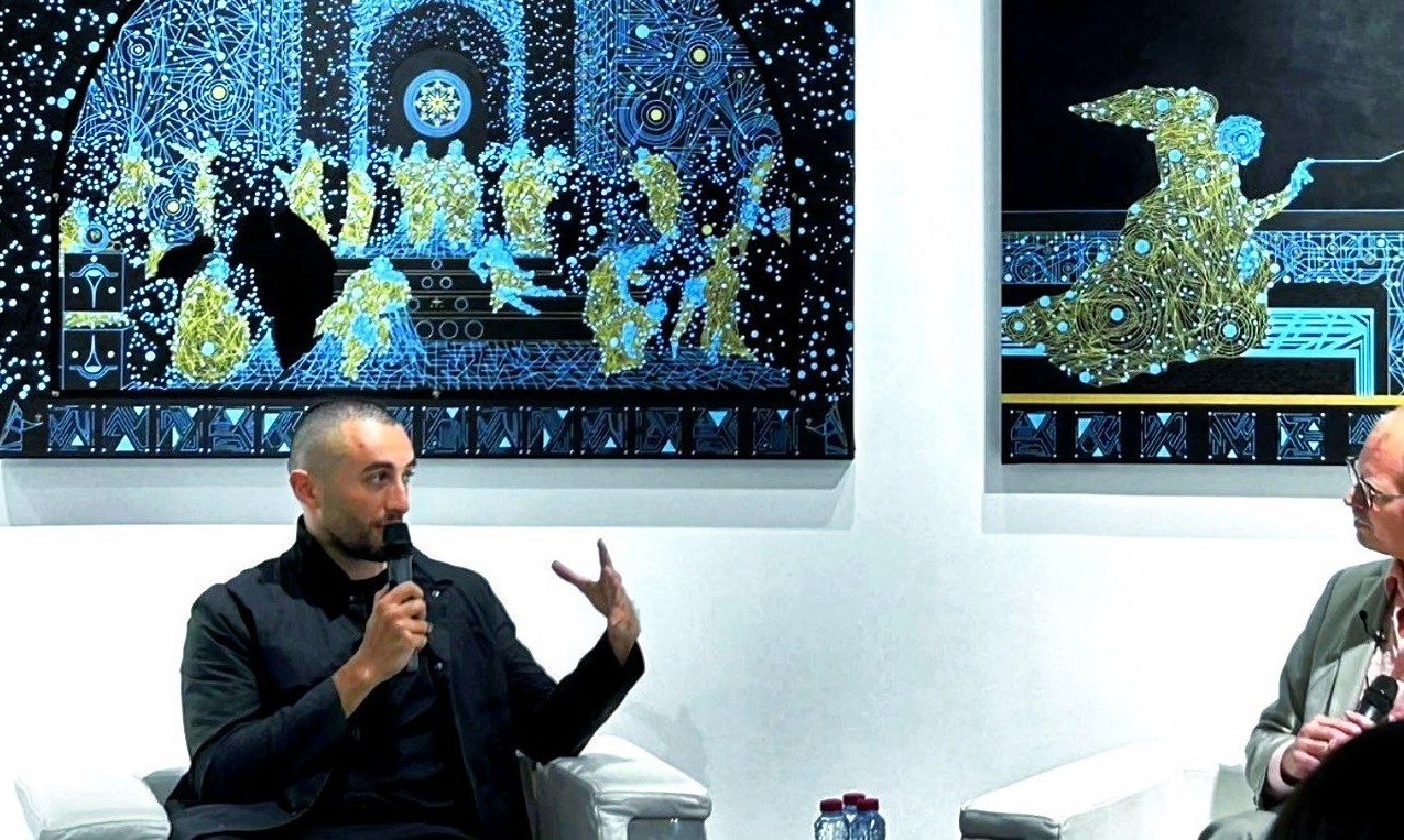 Kaikhan Salakhov discussing his art, with paintings reflecting his vision of space exploration and human evolution.