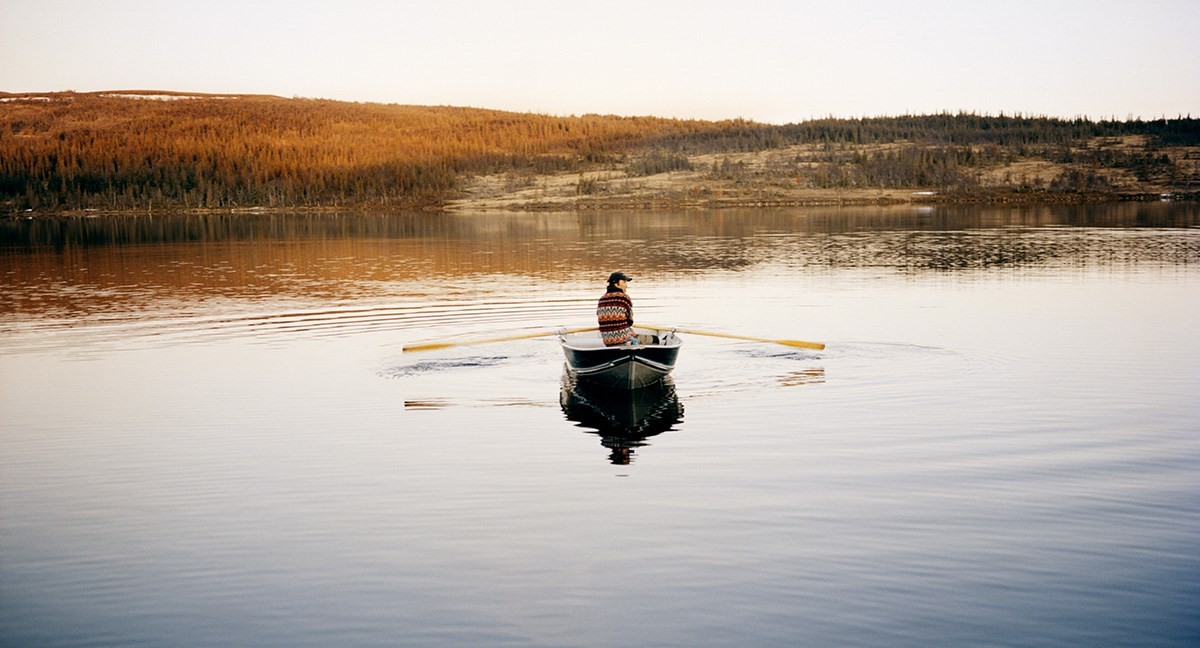 A man rowing in a small boat on a swedish lake during autumn