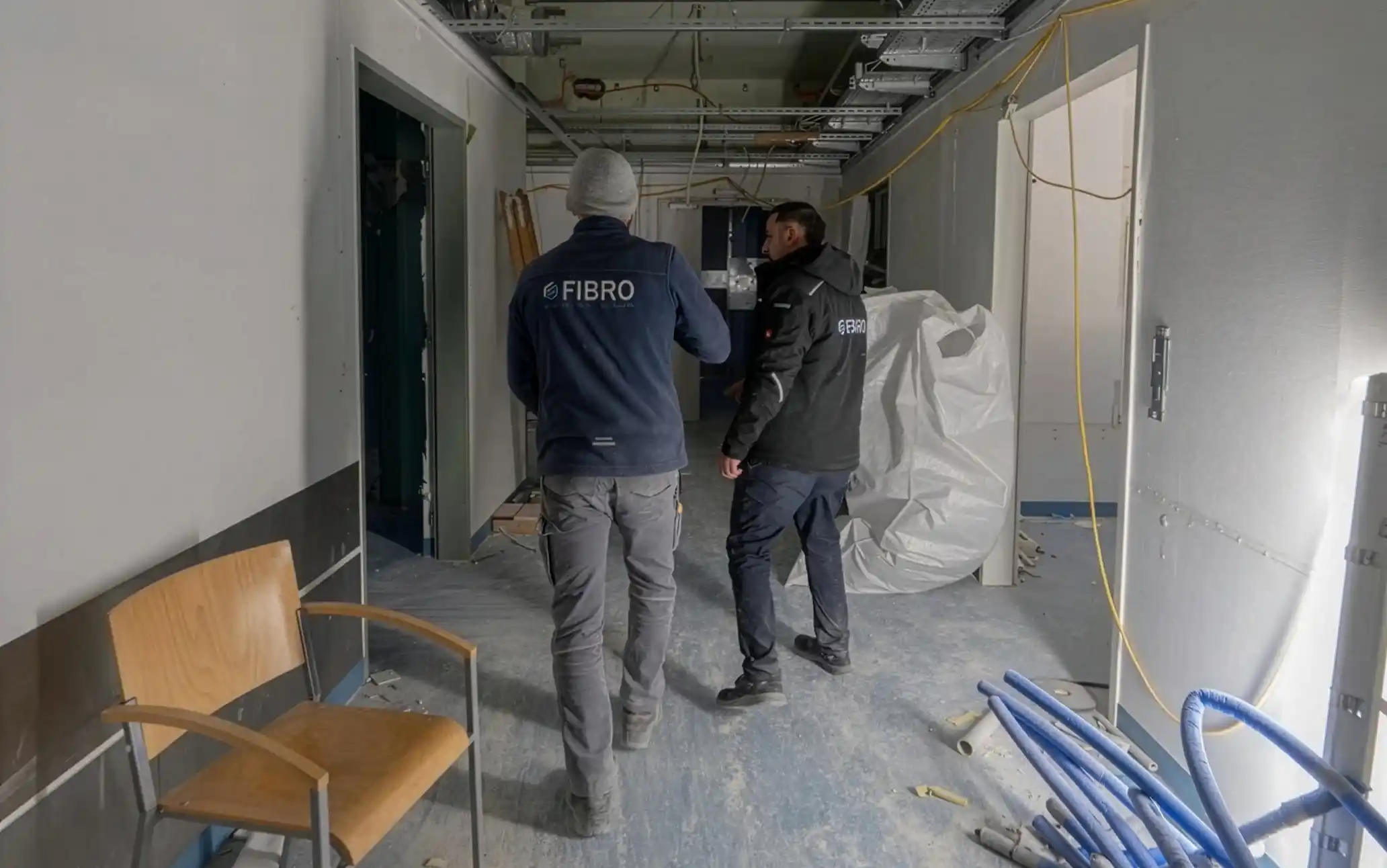 Mitarbeiter koordinieren Rückbauarbeiten im Innenbereich einer Baustelle