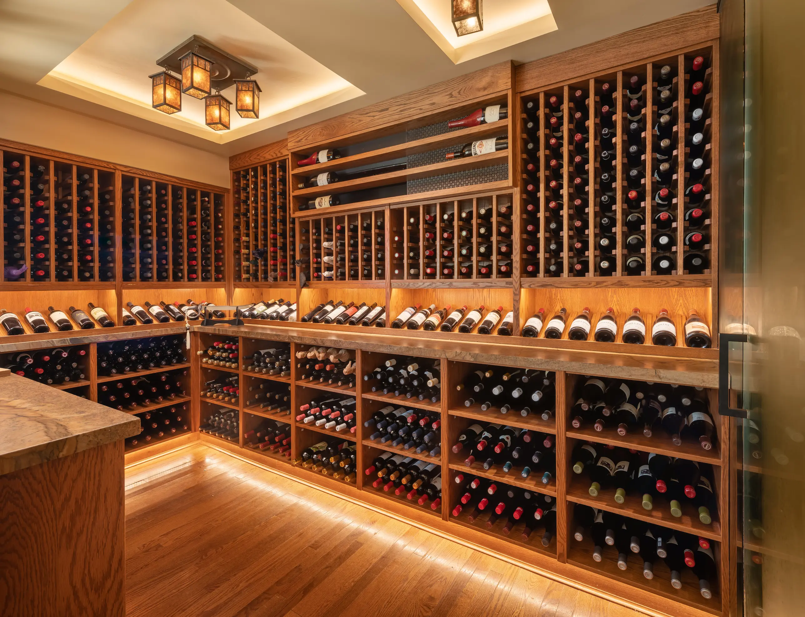 A stylish split-level loft room with an elevated queen bed, modern writing desk below, and floor-to-ceiling windows framing a glowing sunset.