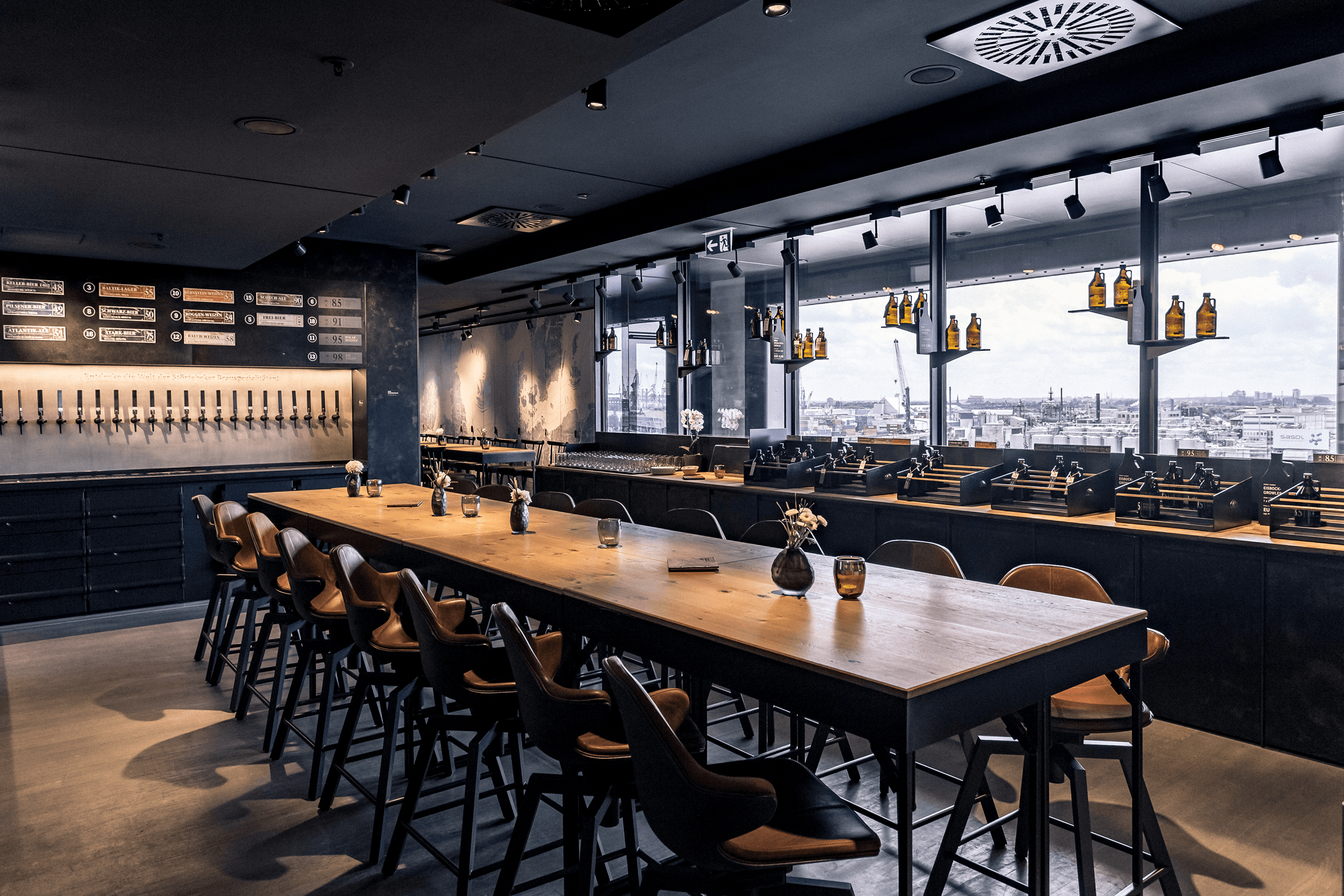 Long wooden table with bar stools in a modern bar.