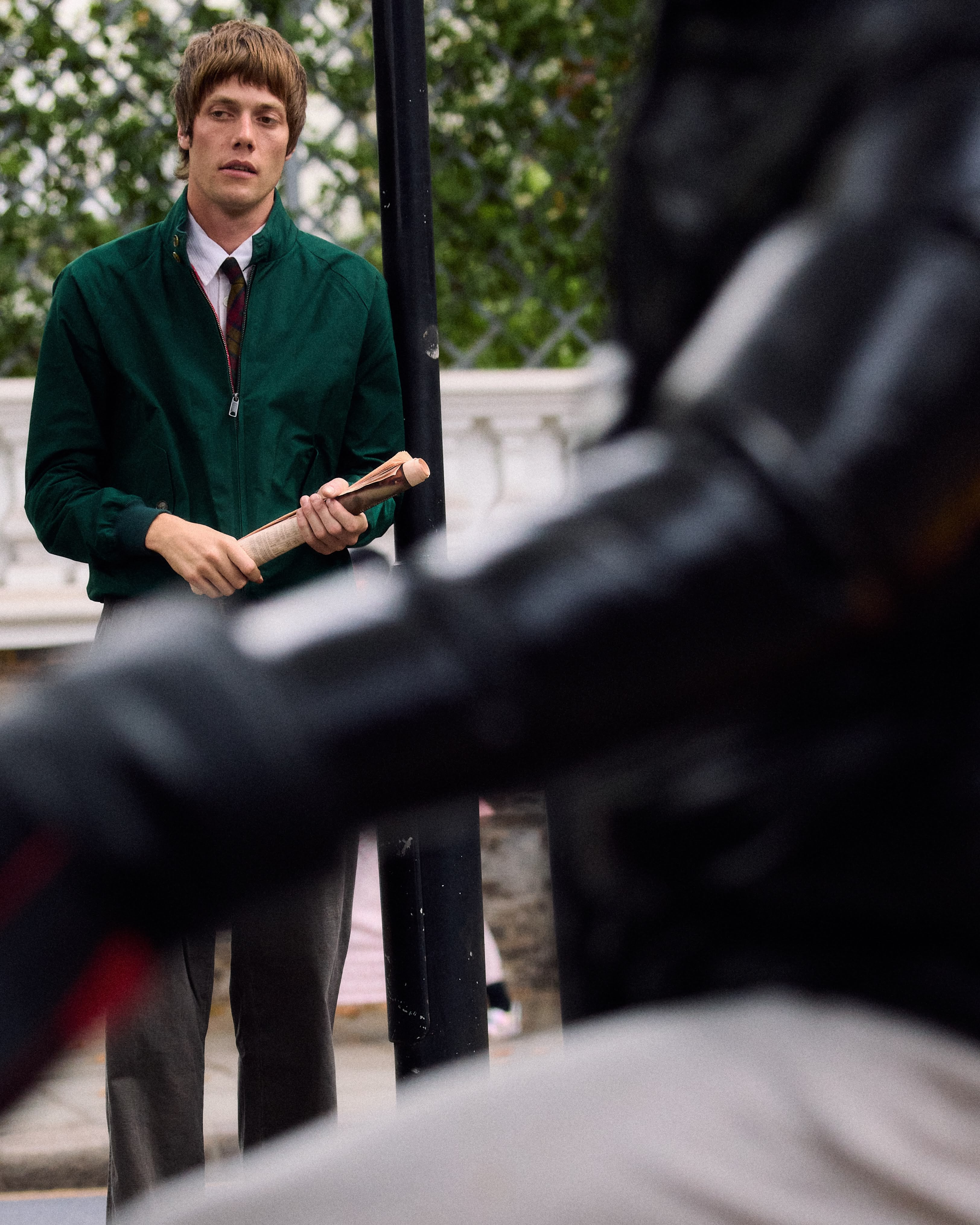 Au second plan, le mannequin porte un blouson en coton vert de la marque Baracuta