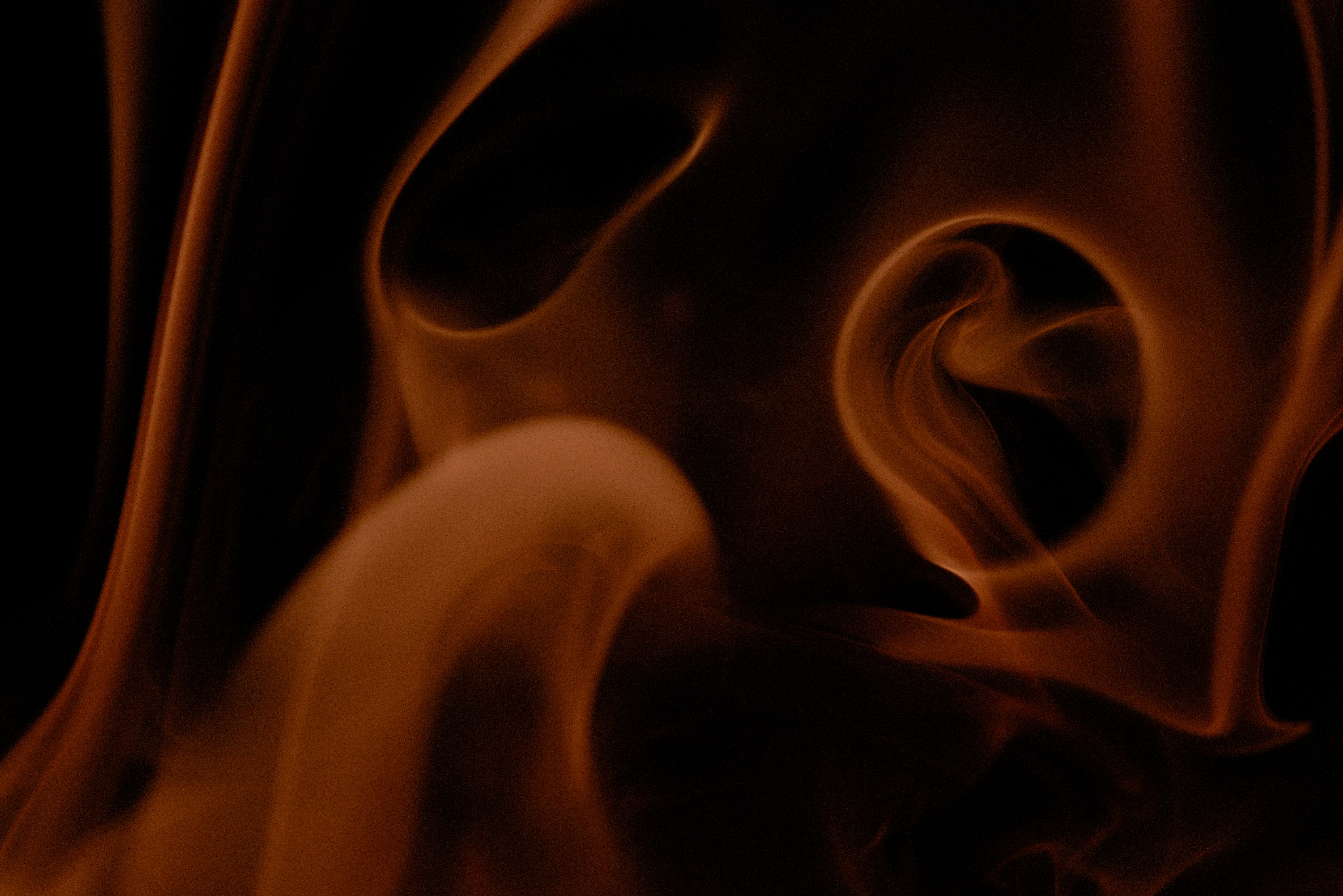Abstract swirling orange smoke against black background