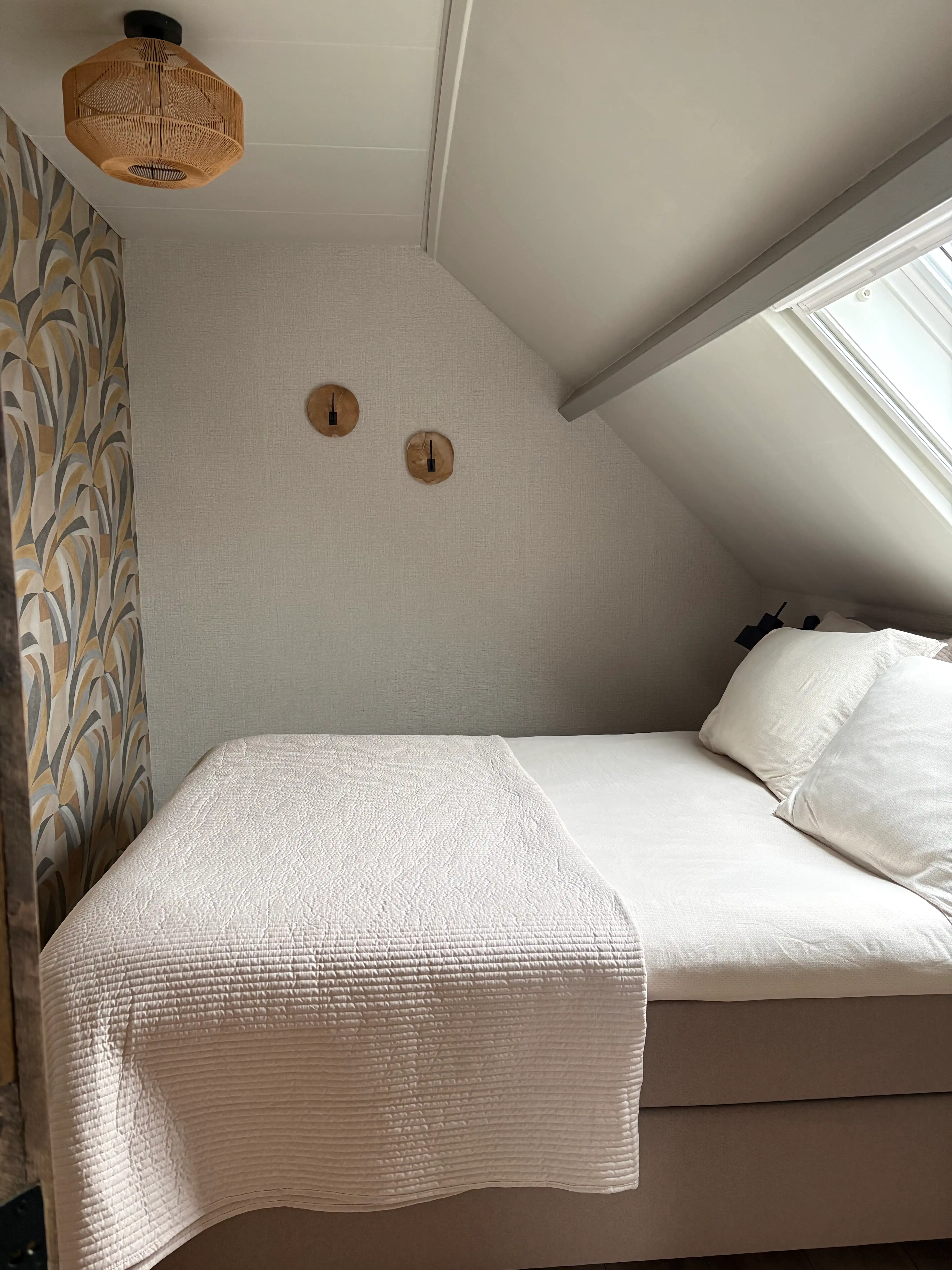 Comfortabel boxspring bed onder een dakraam met natuurlijke lichtinval in Drenthe.