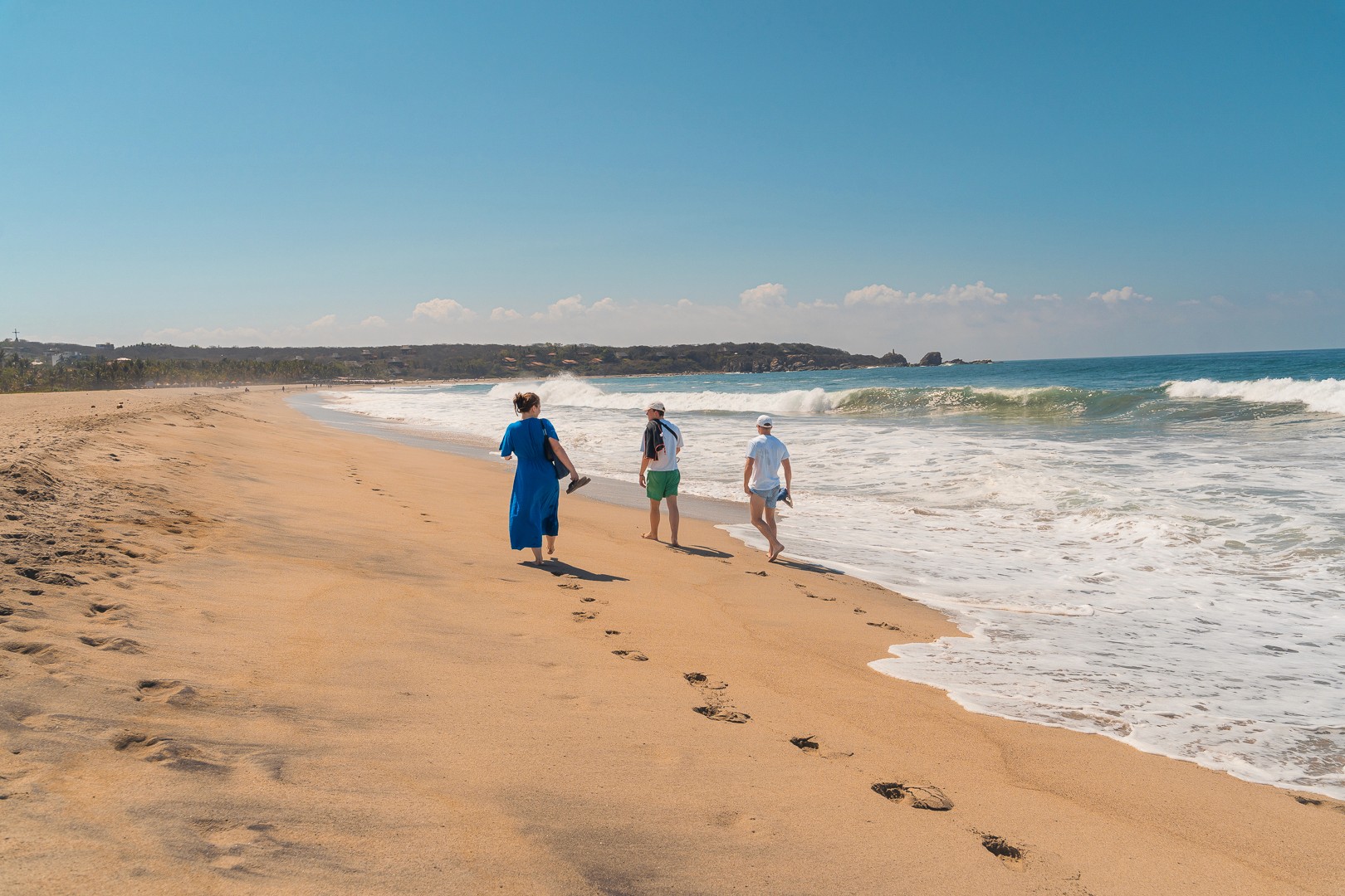 Trois personnes marchant le long d'une plage de sable à Puerto Escondido.