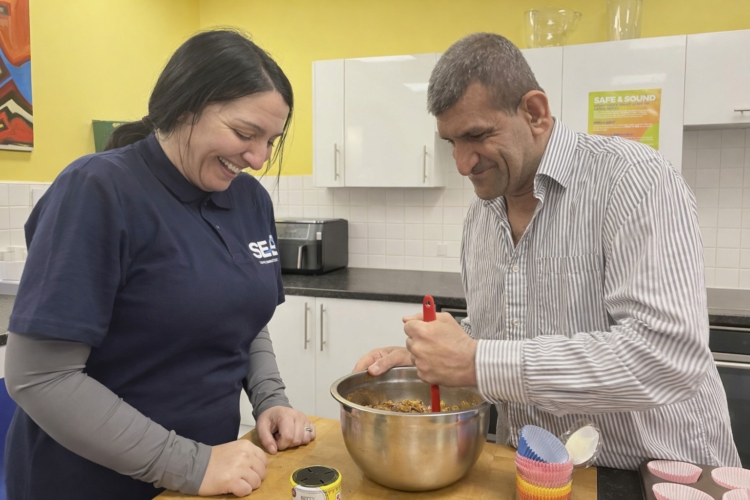 A support worker helping a deaf man bake
