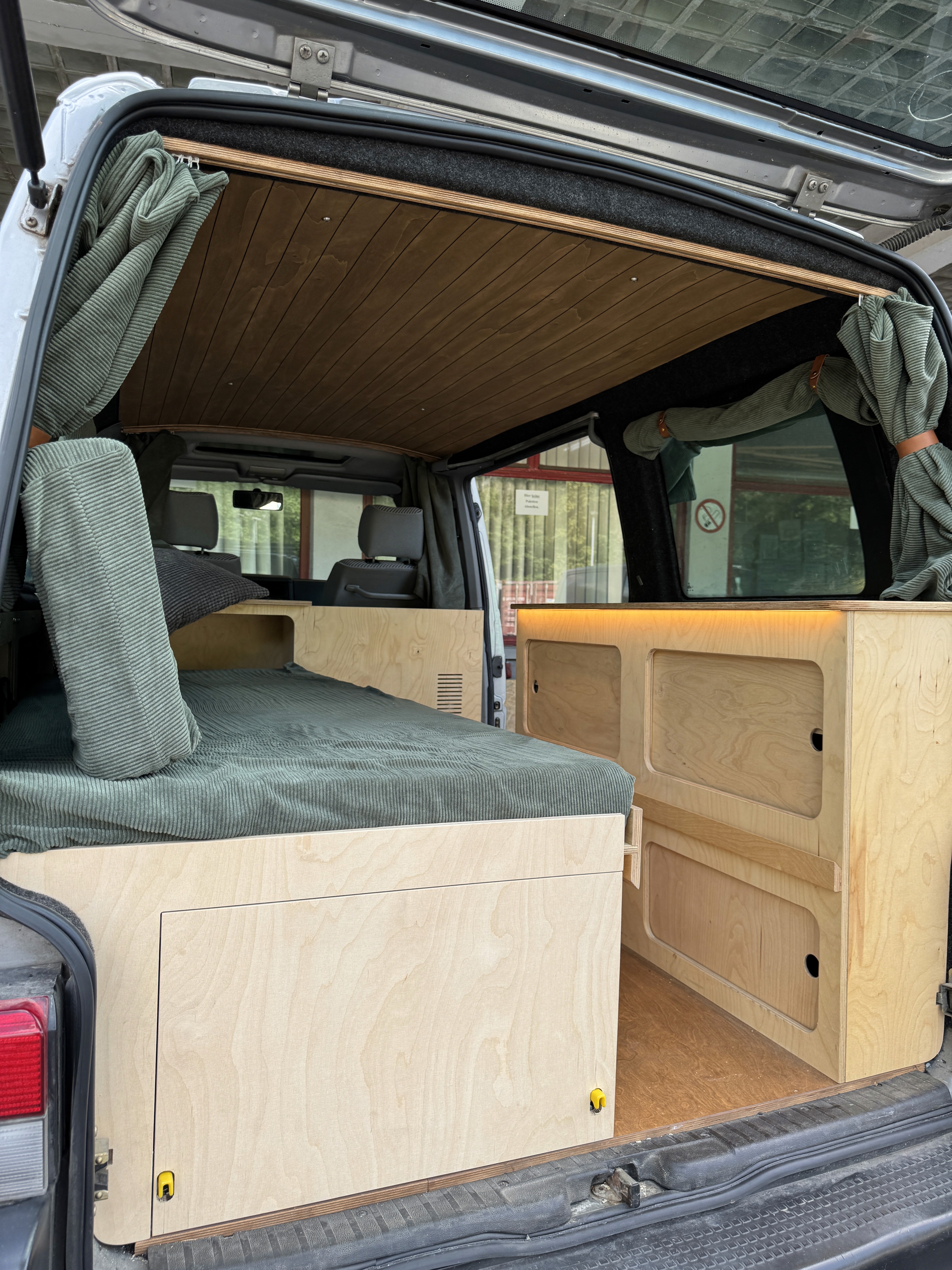 A cozy room with a wooden desk, computer, and warm sunlight streaming through a window.