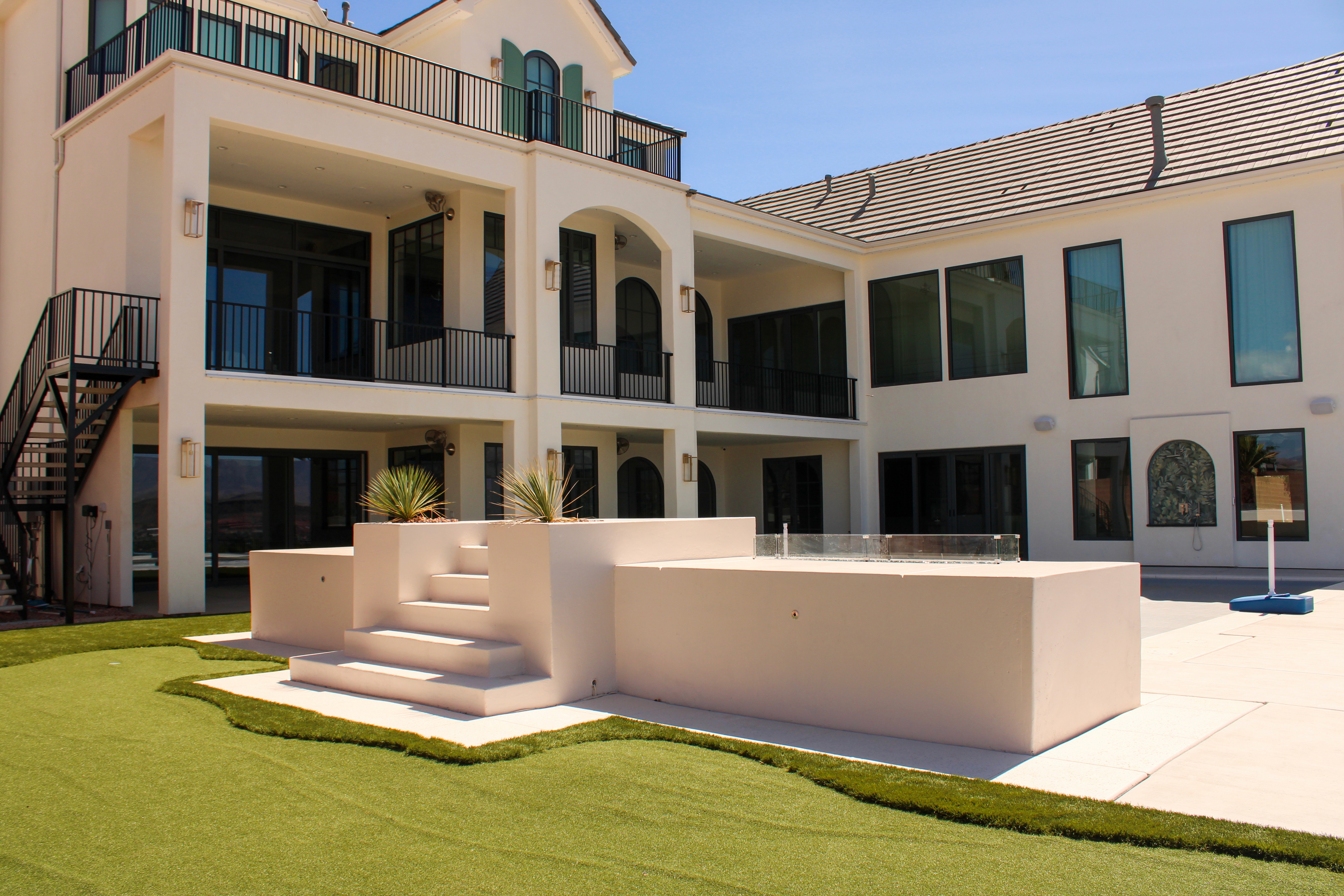Backyard of a St. George, Utah home with a custom built jumping platform next to pool, concrete, and turf.