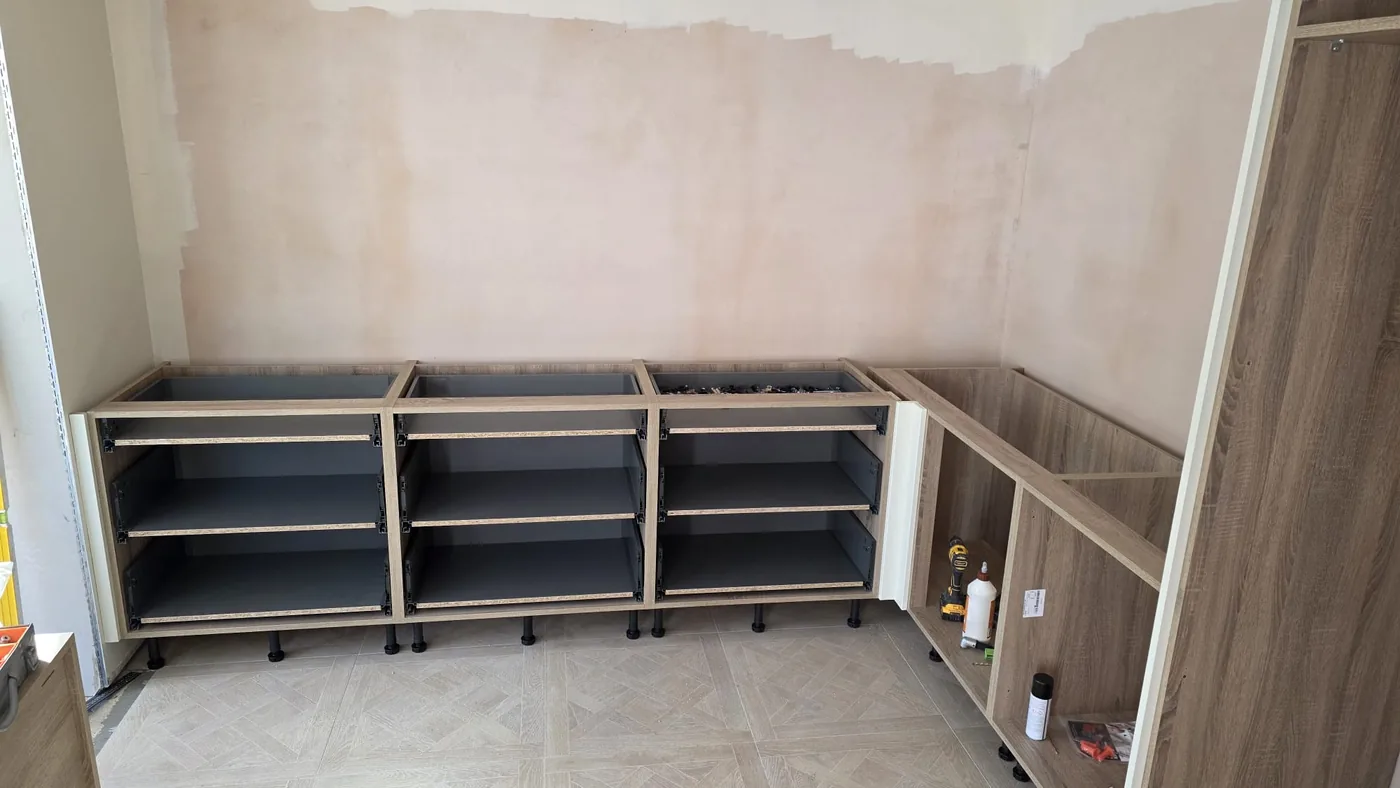 Kitchen carcasses levelled on legs against bare plaster