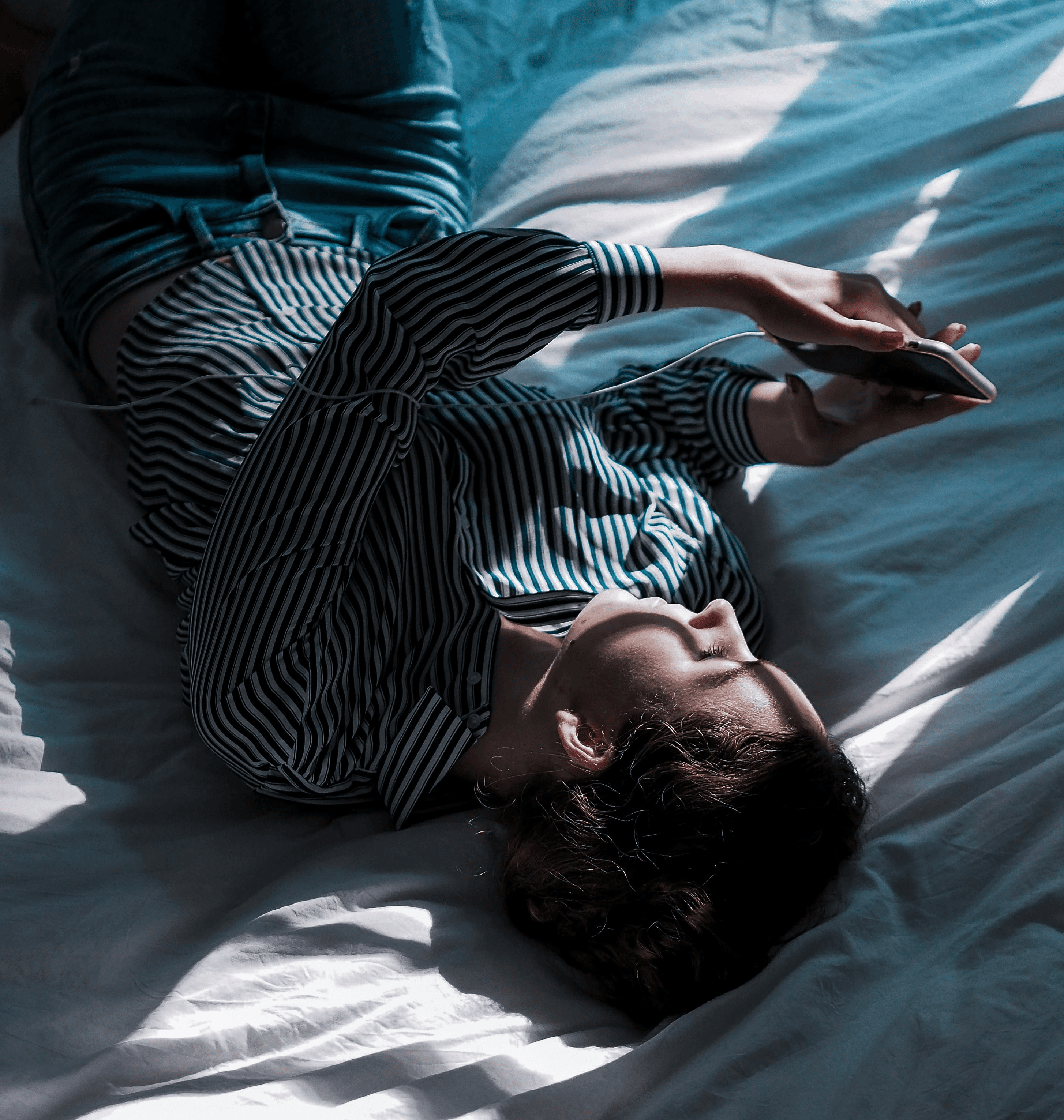 woman in black and white stripe long sleeve shirt lying on bed