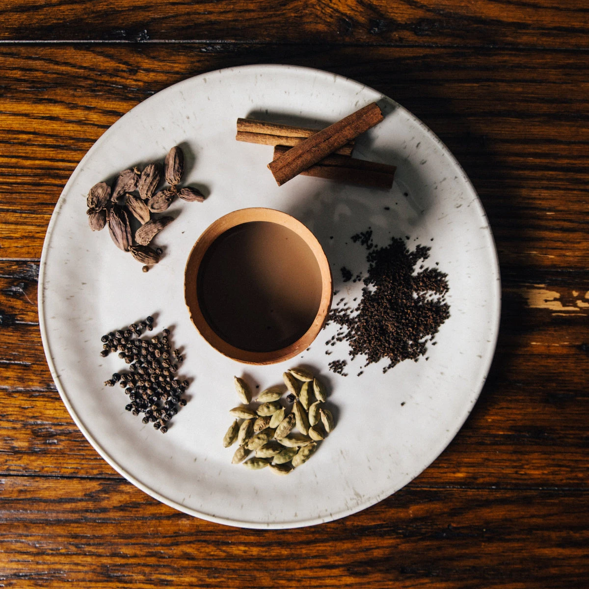 Chai spices and loose tea arranged around a cup