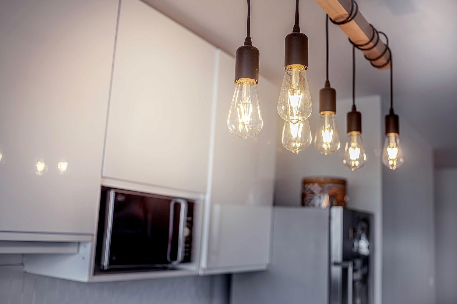 Suspensions industrielles au-dessus d’une cuisine blanche contemporaine.