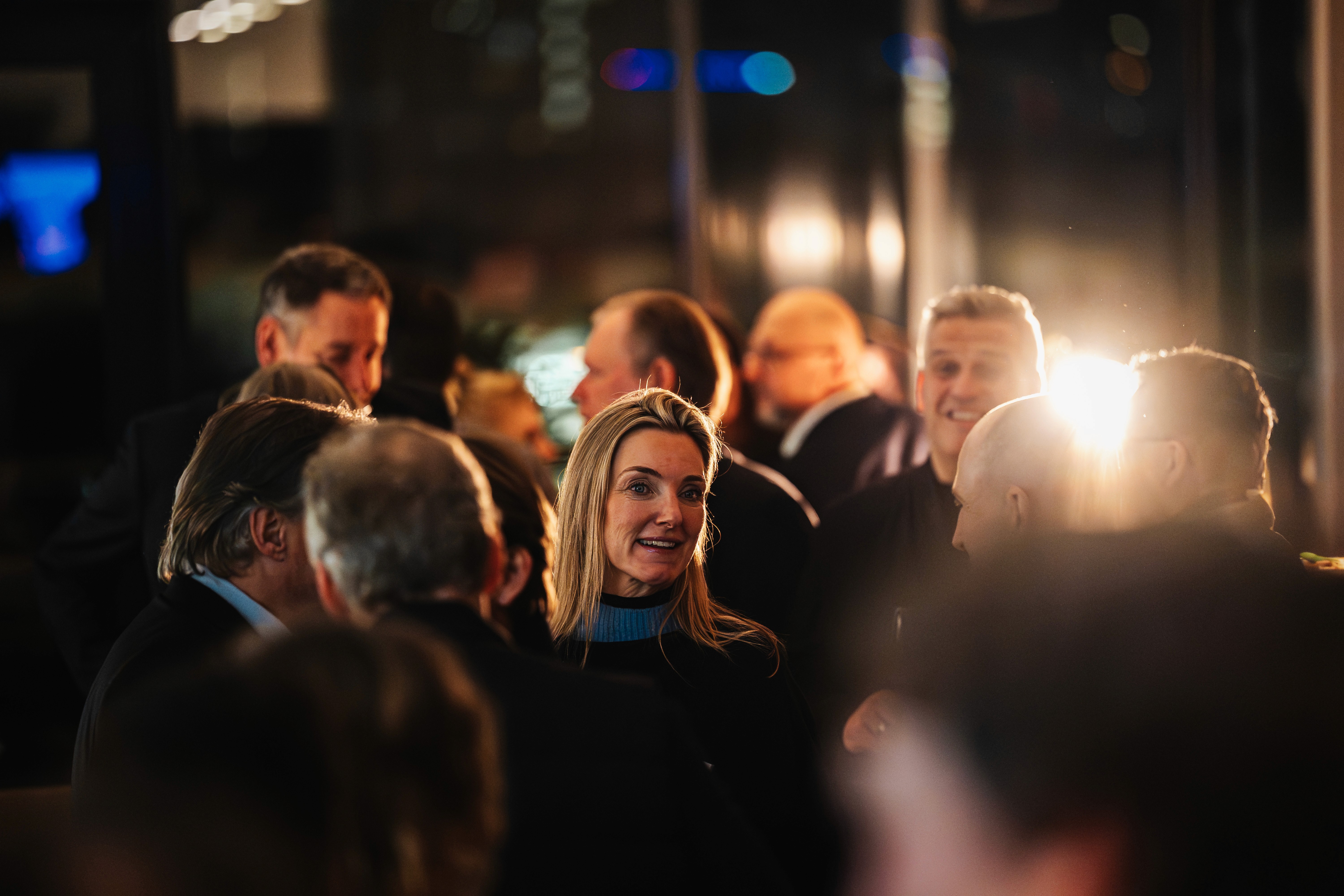 People crossing a busy street with cars and buildings.