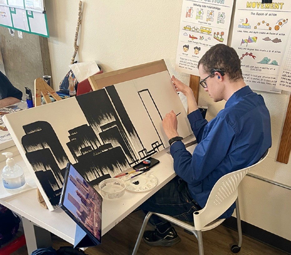 Access Gallery artist Matt Maclean creates artwork in the studio, depicting a skyline on white canvas with black images.