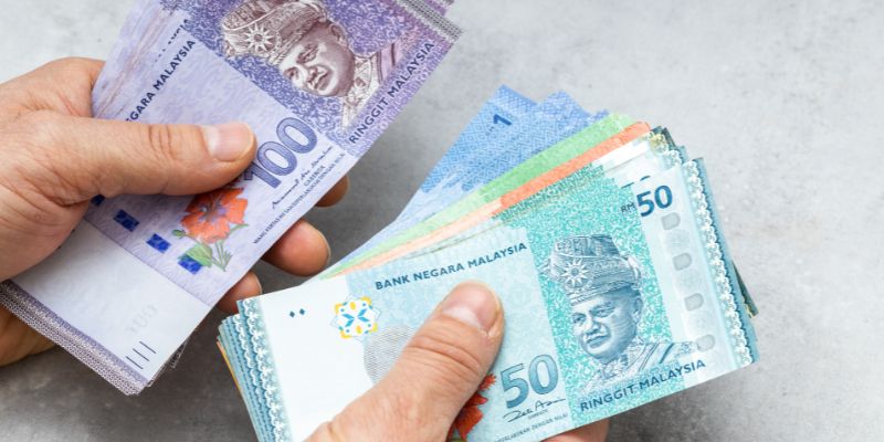 A person counting Malaysian ringgit