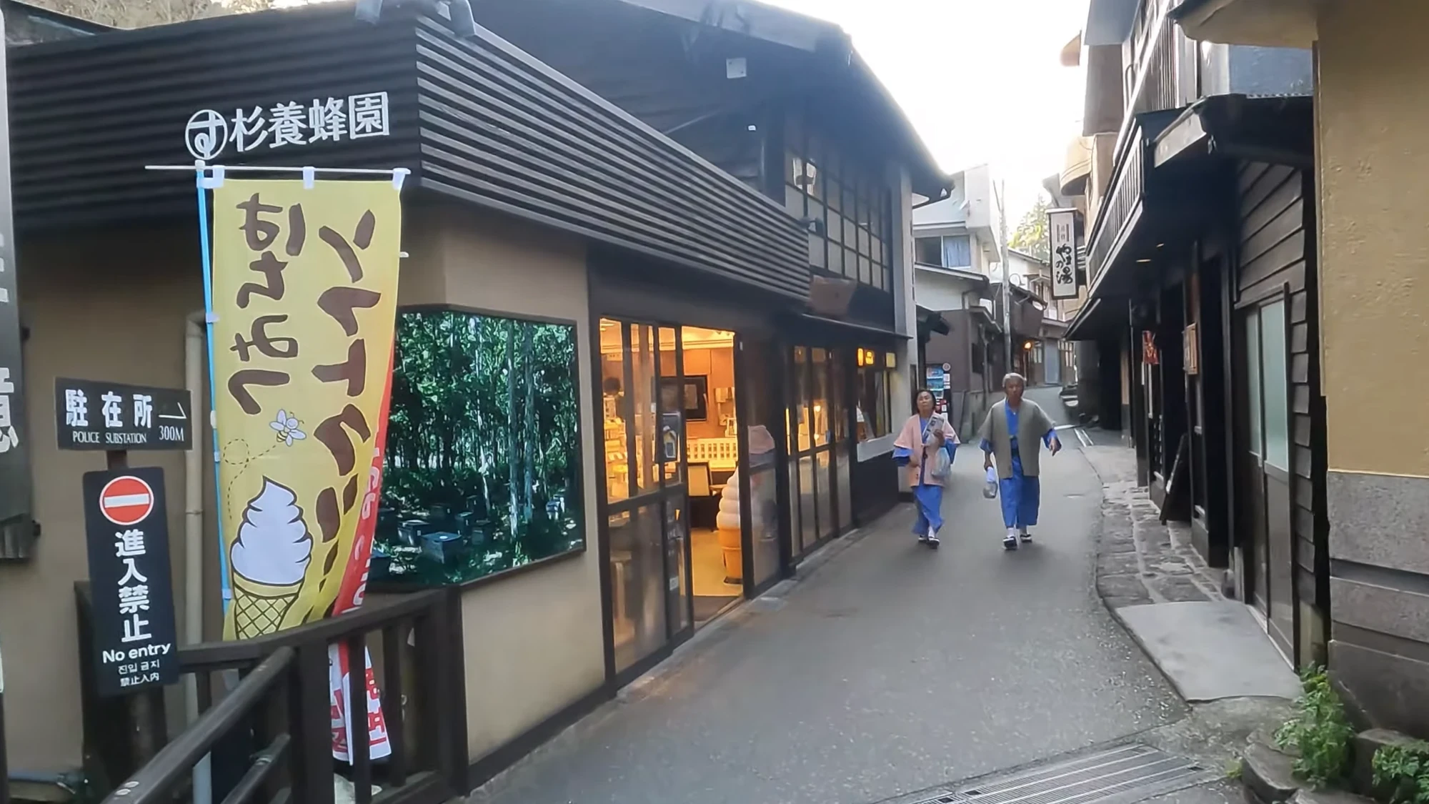 Two guests in yukata with haori jackets over them walking a shopfront lane at Kurokawa Onsen