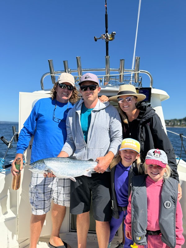 Family on a charter boat holding a freshly caught salmon