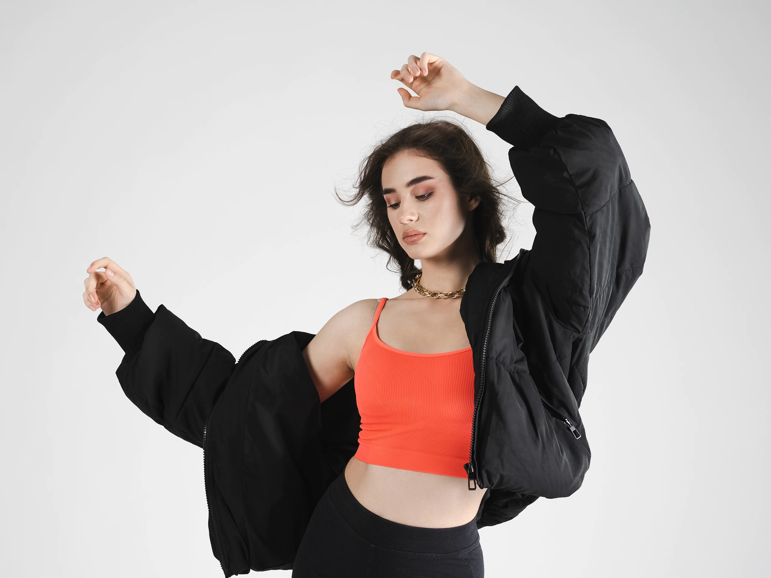 Fashion portrait of a woman in a red top and black jacket, captured in dynamic motion.