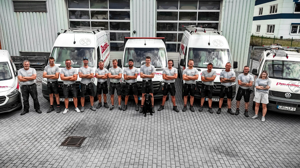 Team der Dachdeckerei Paustian vor den Firmenfahrzeugen