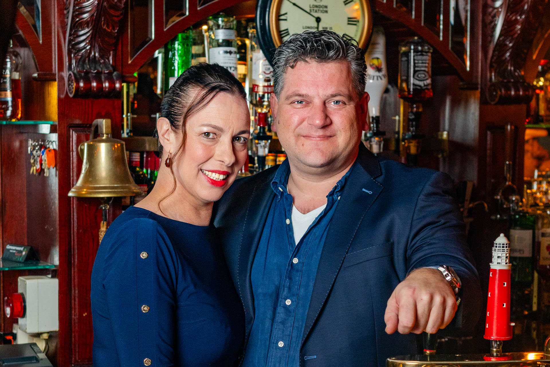 Foto van de eigenaren lachend achter de bar