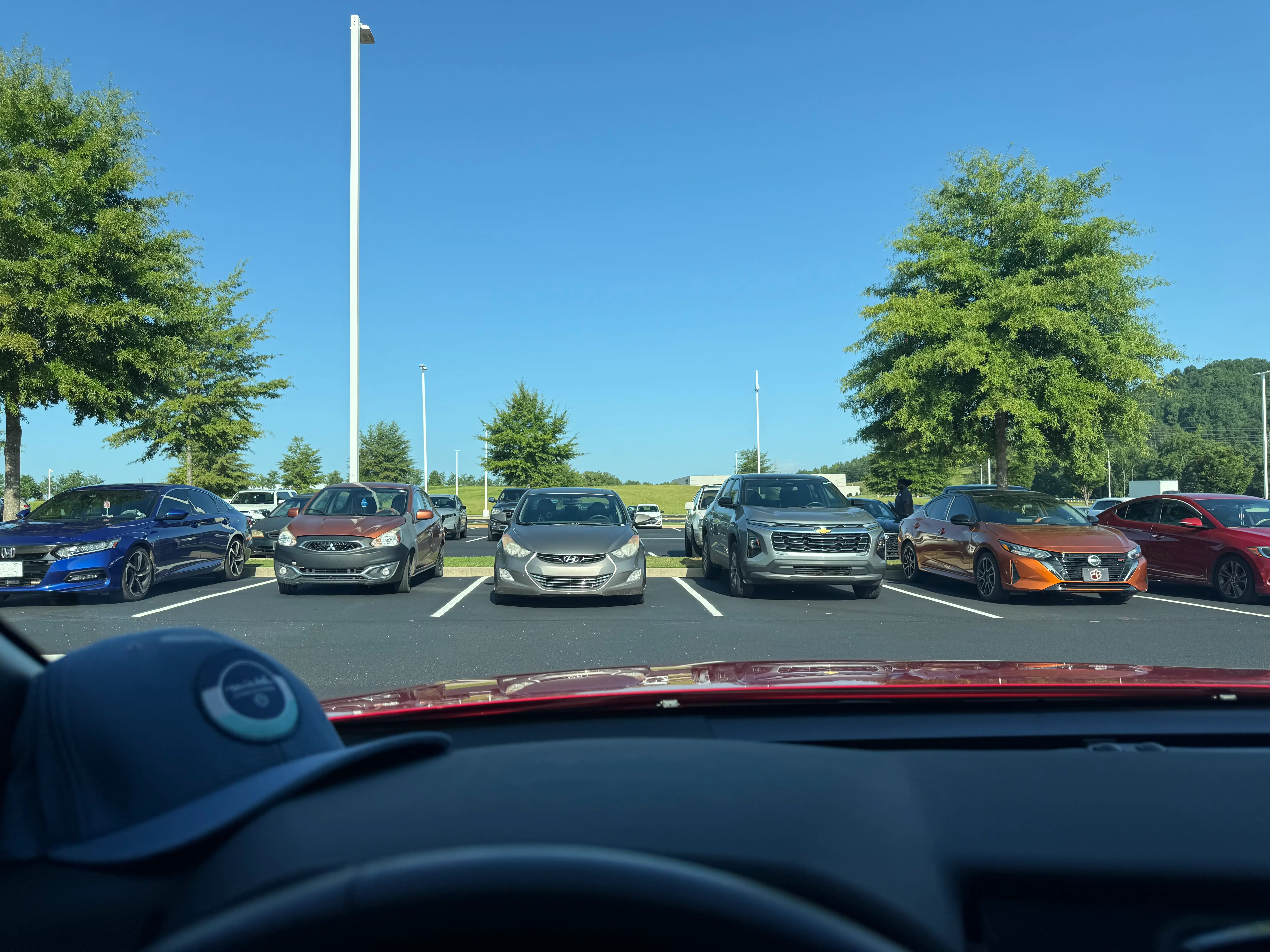 View from inside a parked car during a lunch break, looking out across a workplace parking lot, capturing a quiet moment of reflection about purpose, patience, and life's changing seasons.