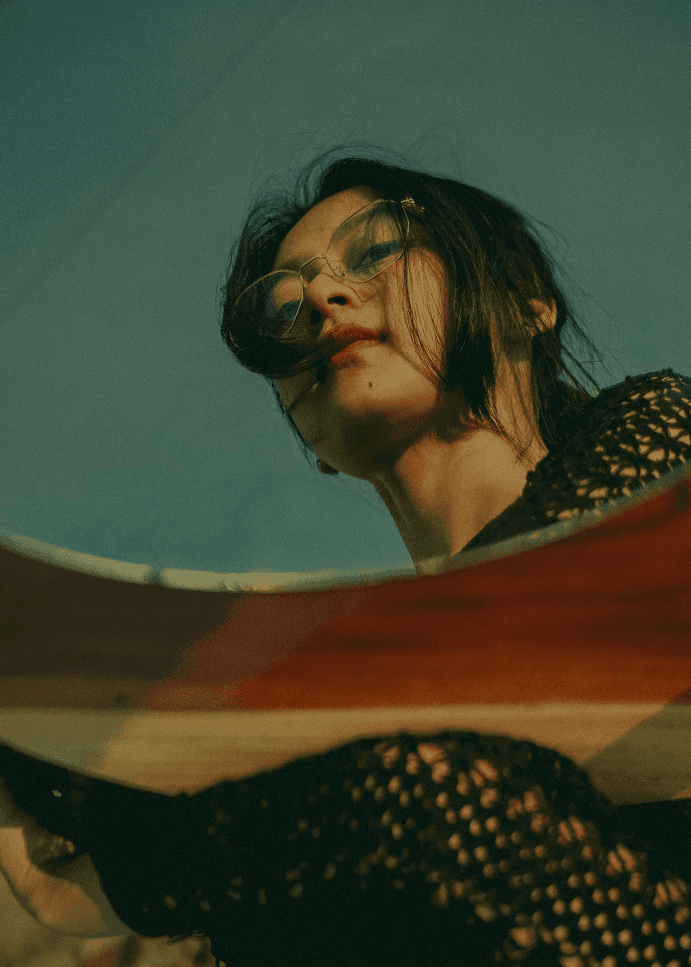 A person wearing sunglasses, photographed from a low angle against the sky.