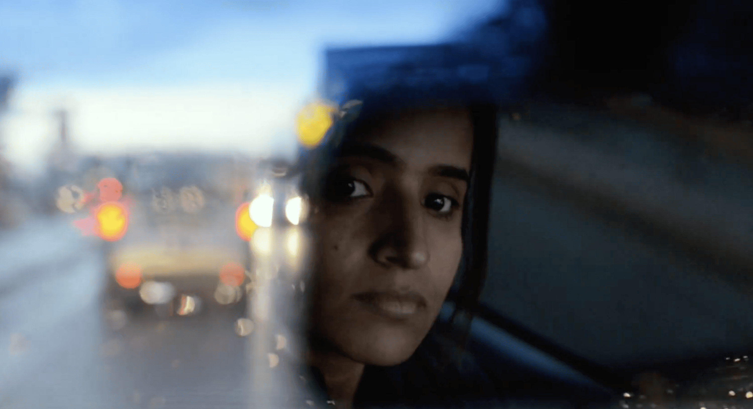 A black and white profile portrait of a person with long hair, accented by sparkling, glittery light effects throughout the frame.