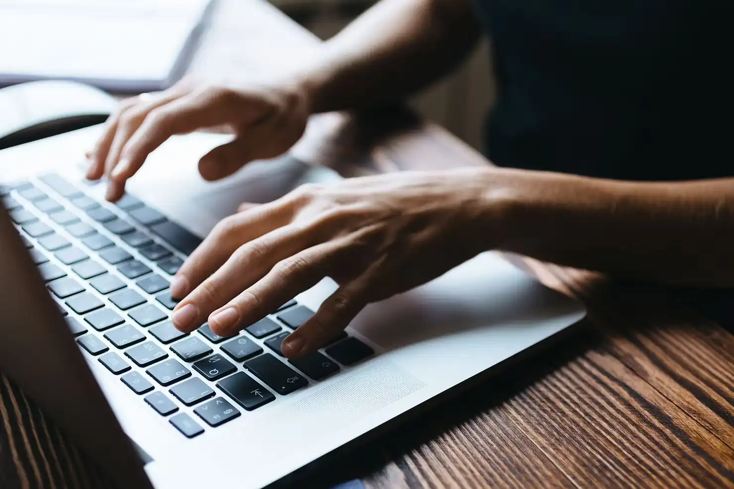 Marketer typing on a laptop using AI and automation tools in a digital marketing agency.