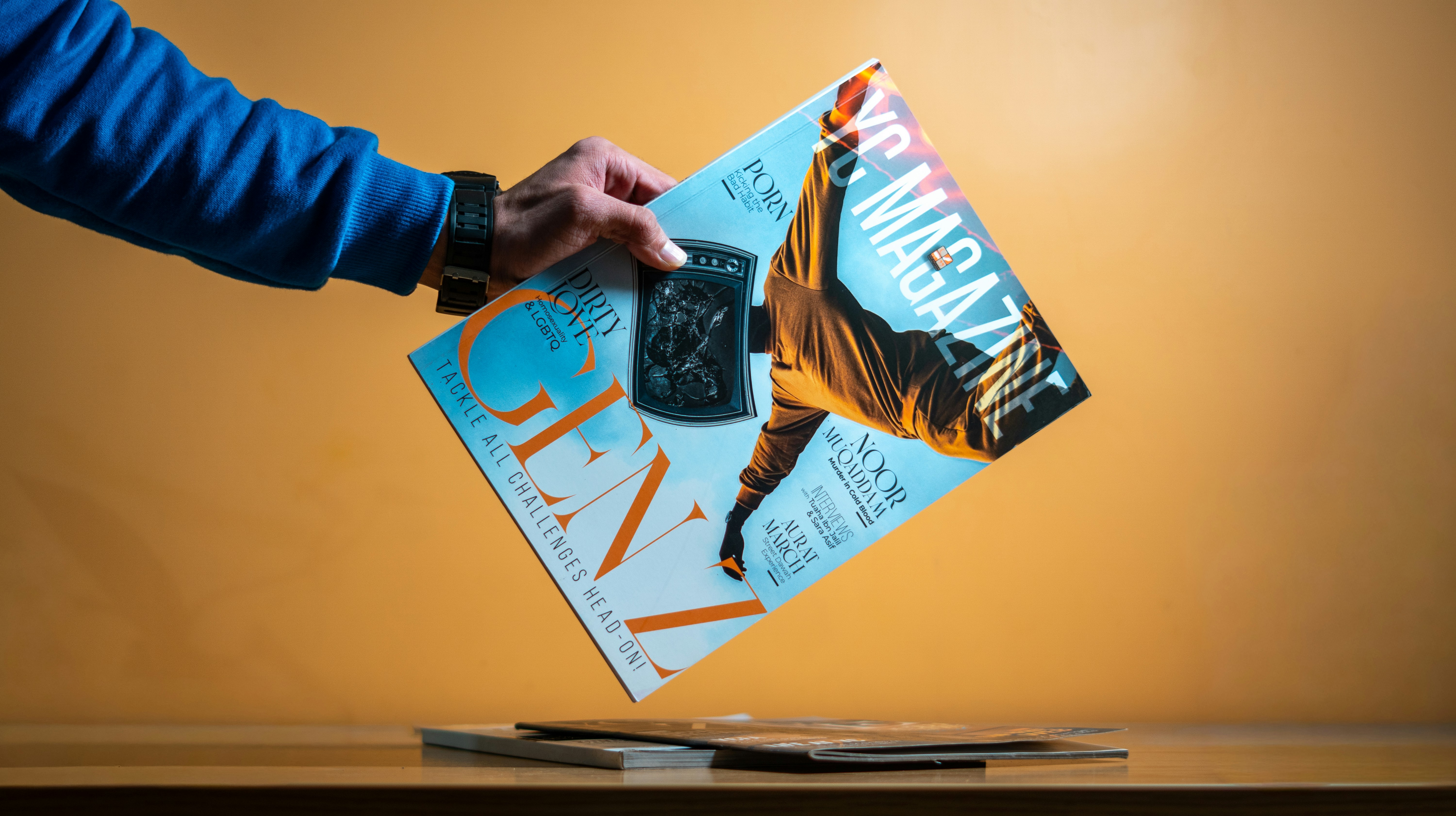 Hand holding a magazine over a stack of magazines