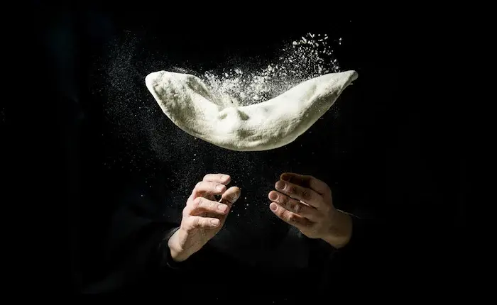 photo montage de deux mains qui jettent un pâton à pizza en l'air pour simuler l'étalage accrobatique