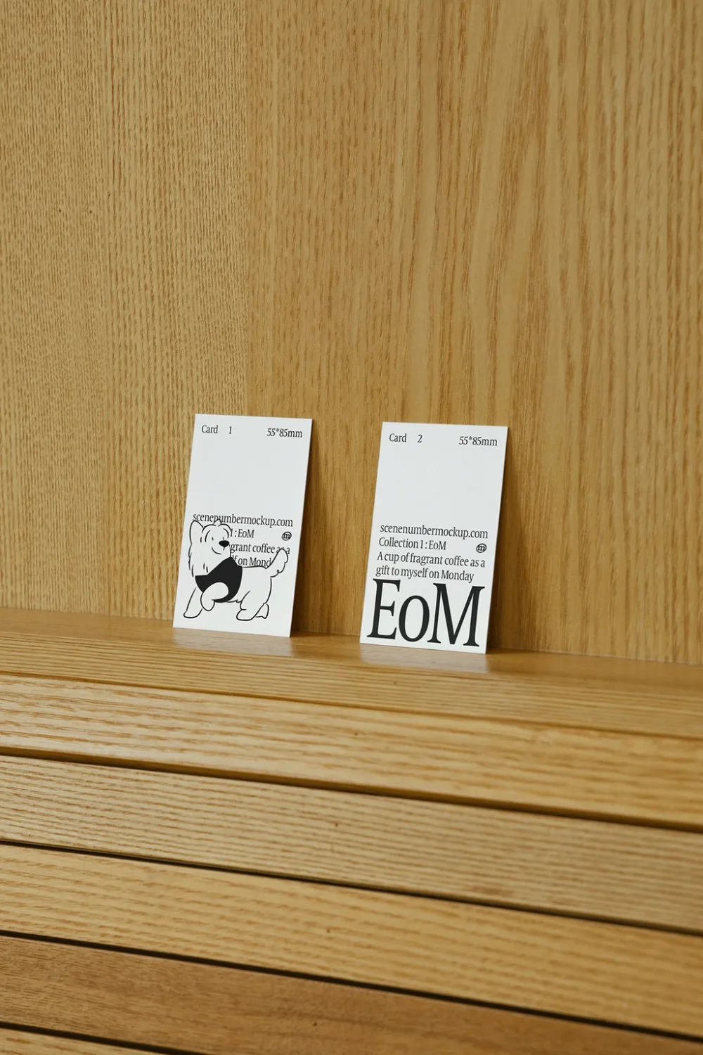 Two colorful card mockups, one yellow and one green, displayed upright on a wooden surface with a natural oak texture. The minimal setup highlights the vibrant designs in a warm indoor setting.