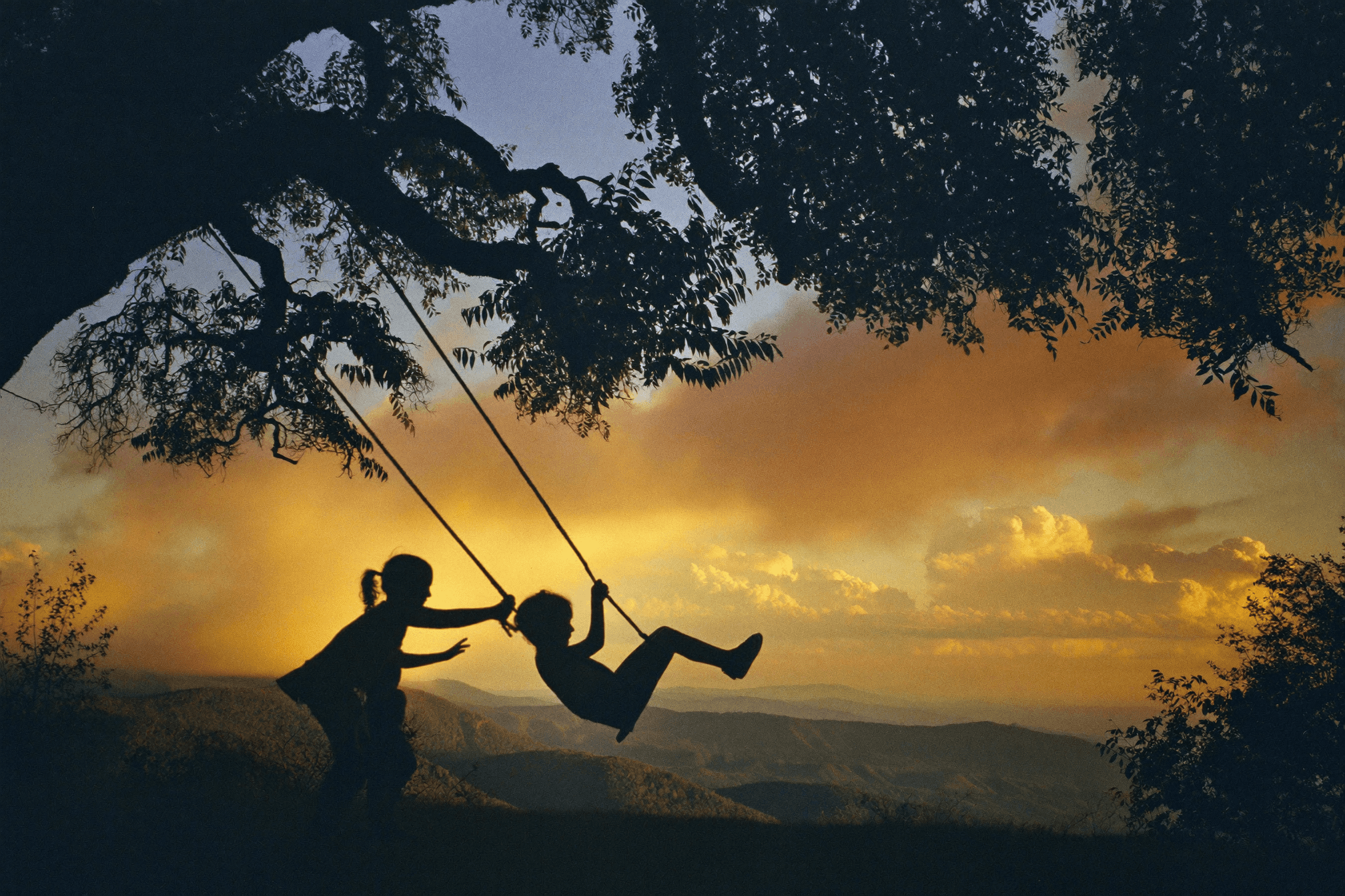 a couple of people sitting on top of a grass covered field