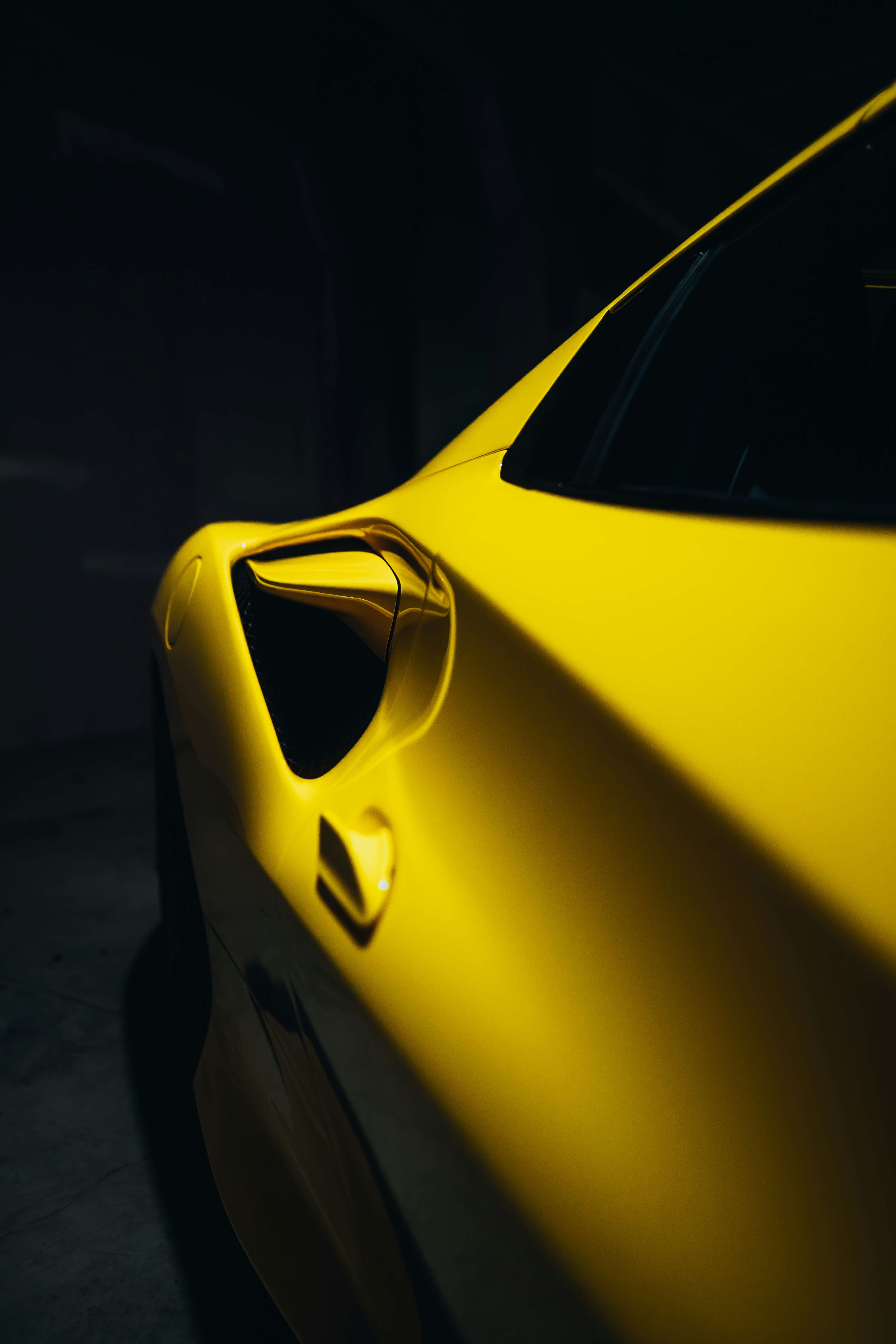 a yellow sports car parked in a dark garage