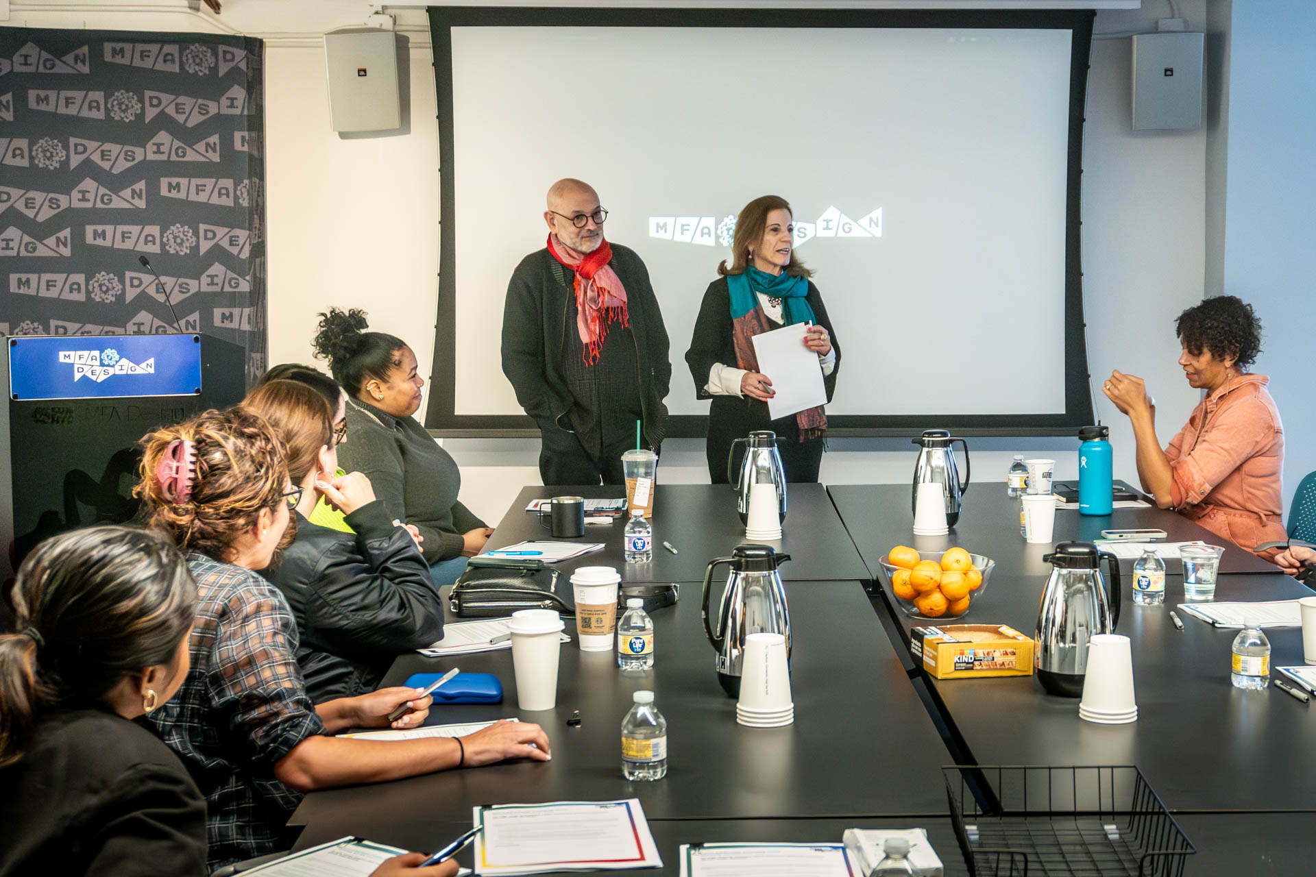two people giving a presentation to a room of people at tables