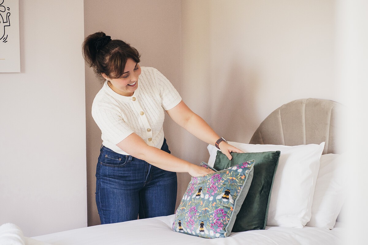Aniko Rucz preparing a guest-ready short-term rental bedroom with attention to cleanliness and presentation